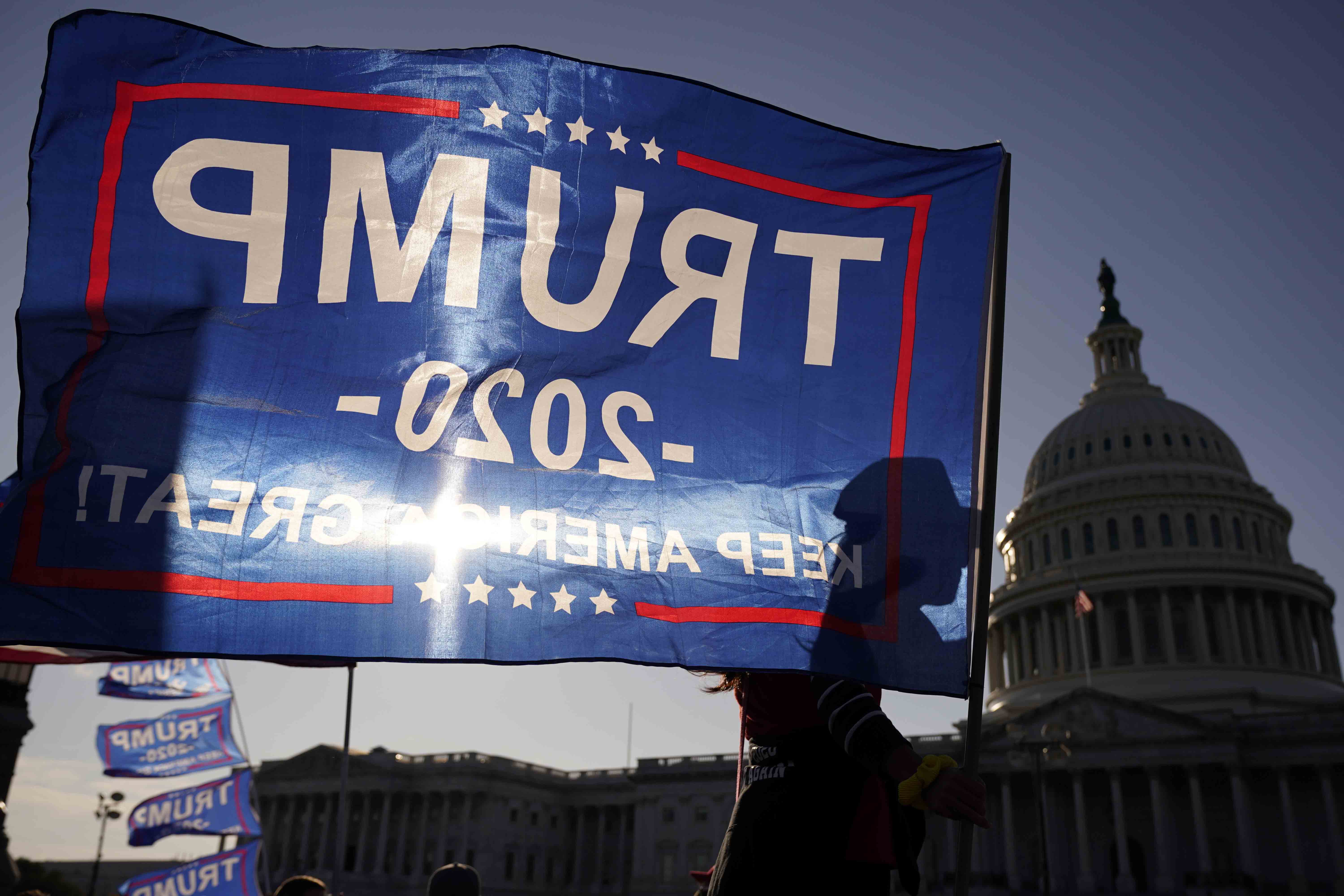 A supporter of President Donald Trump holds a Trump 2020 flag outside the US Capitol building as they attend pro-Trump marches, on November 14, 2020 in Washington [AP/Jacquelyn Martin]