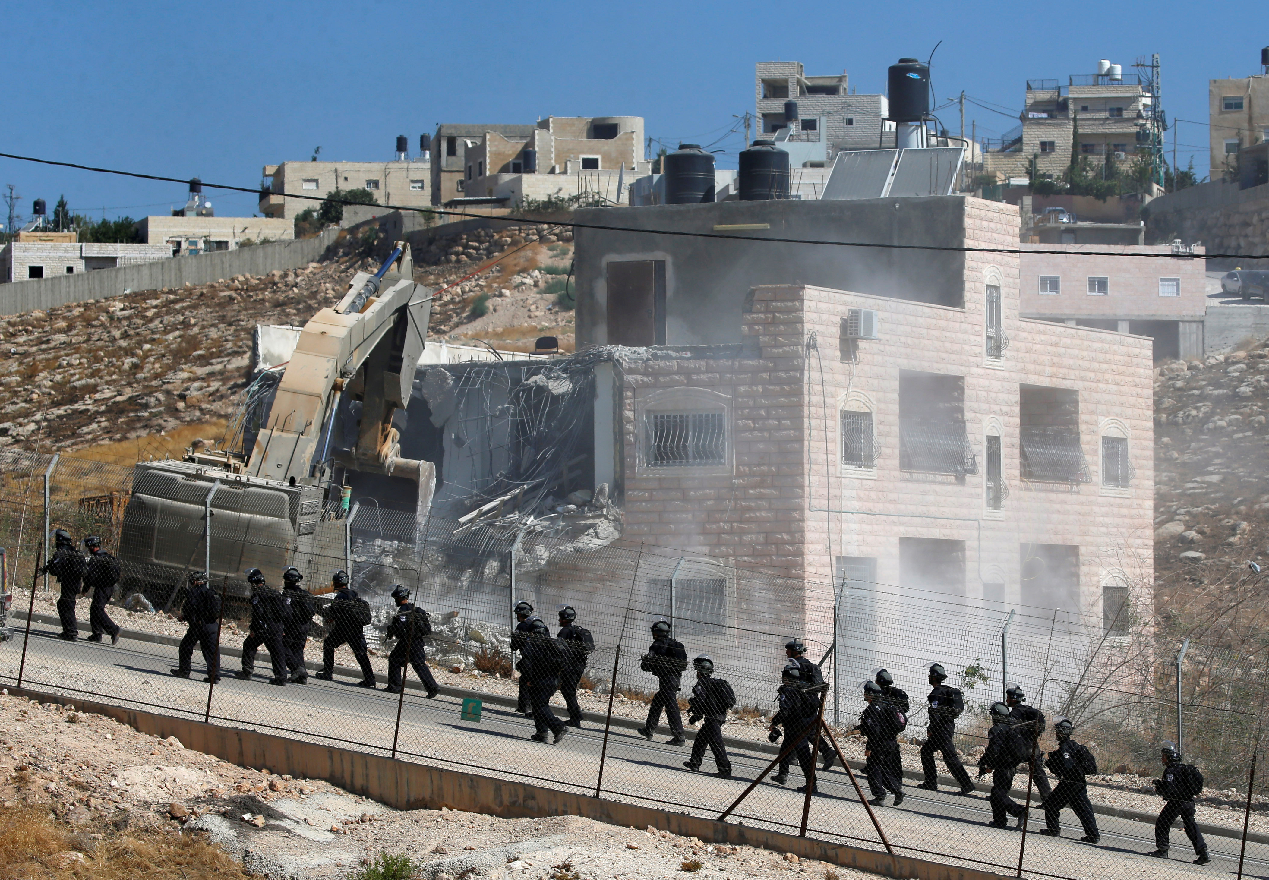Israeli forces patrol as machinery demolishes a Palestinian building in the village of Sur Baher which is divided by the Israeli barrier in East Jerusalem and the Israeli-occupied West Bank on July 22, 2019 [Mussa Qawasma/Reuters]
