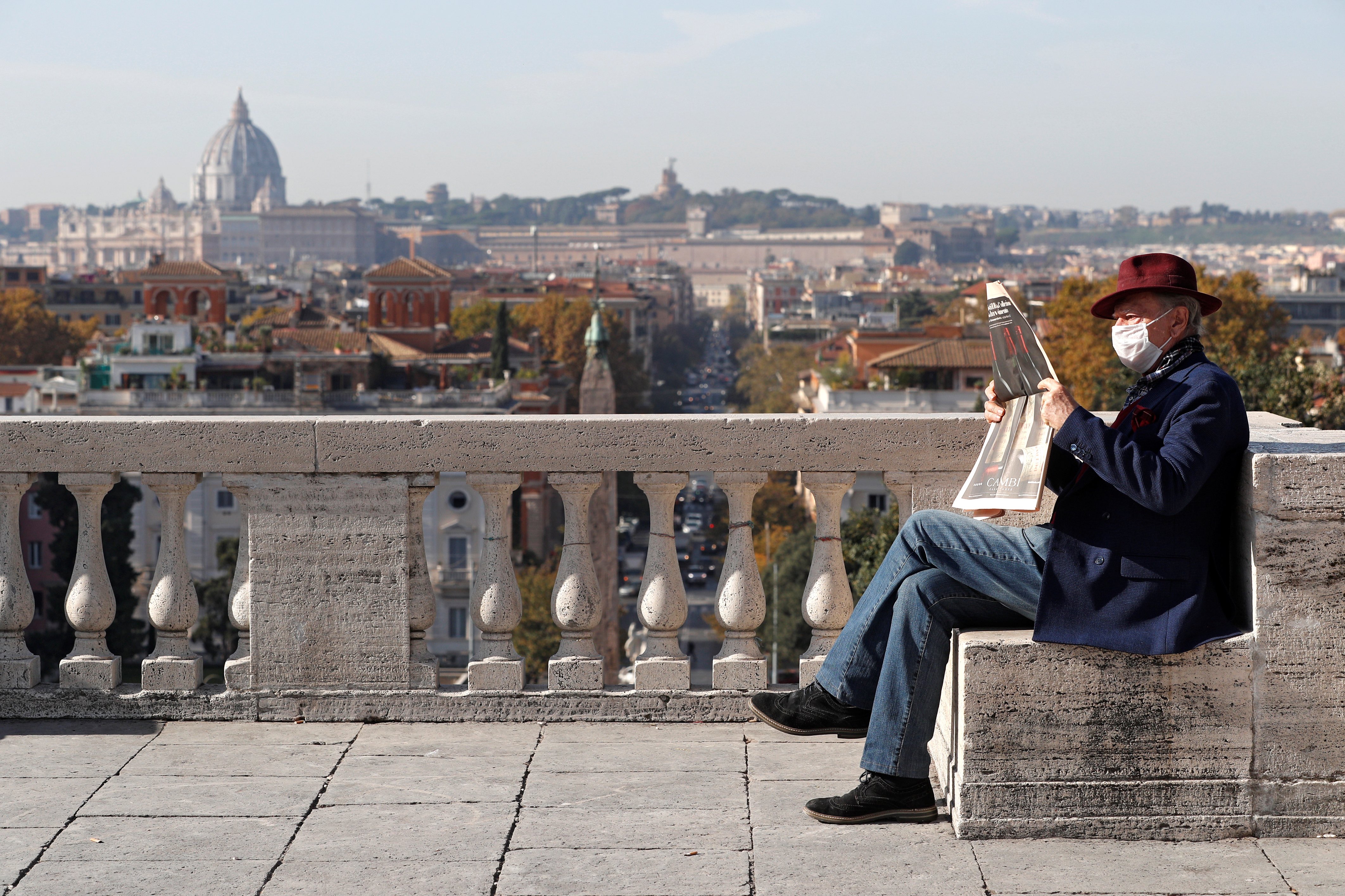 A man wearing a protective face mask reads a newspaper, as the spread of the coronavirus continues, in Rome, Italy [File: Guglielmo Mangiapane/Reuters]