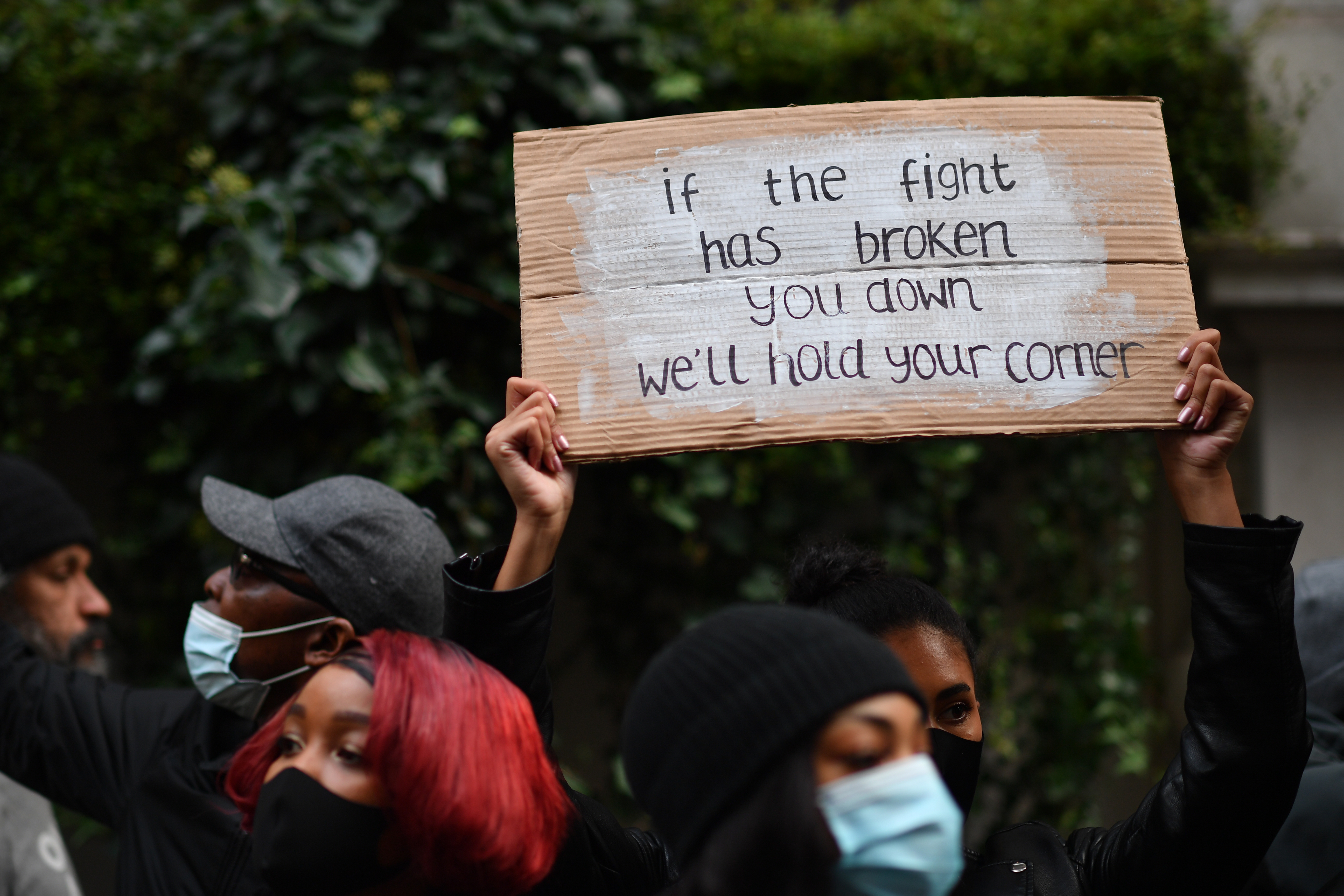 A protester holds a sign in support of #EndSARS demonstrators, at a rally outside the Nigerian High Commission in London on October 25, 2020 [Ben Stansall/AFP]