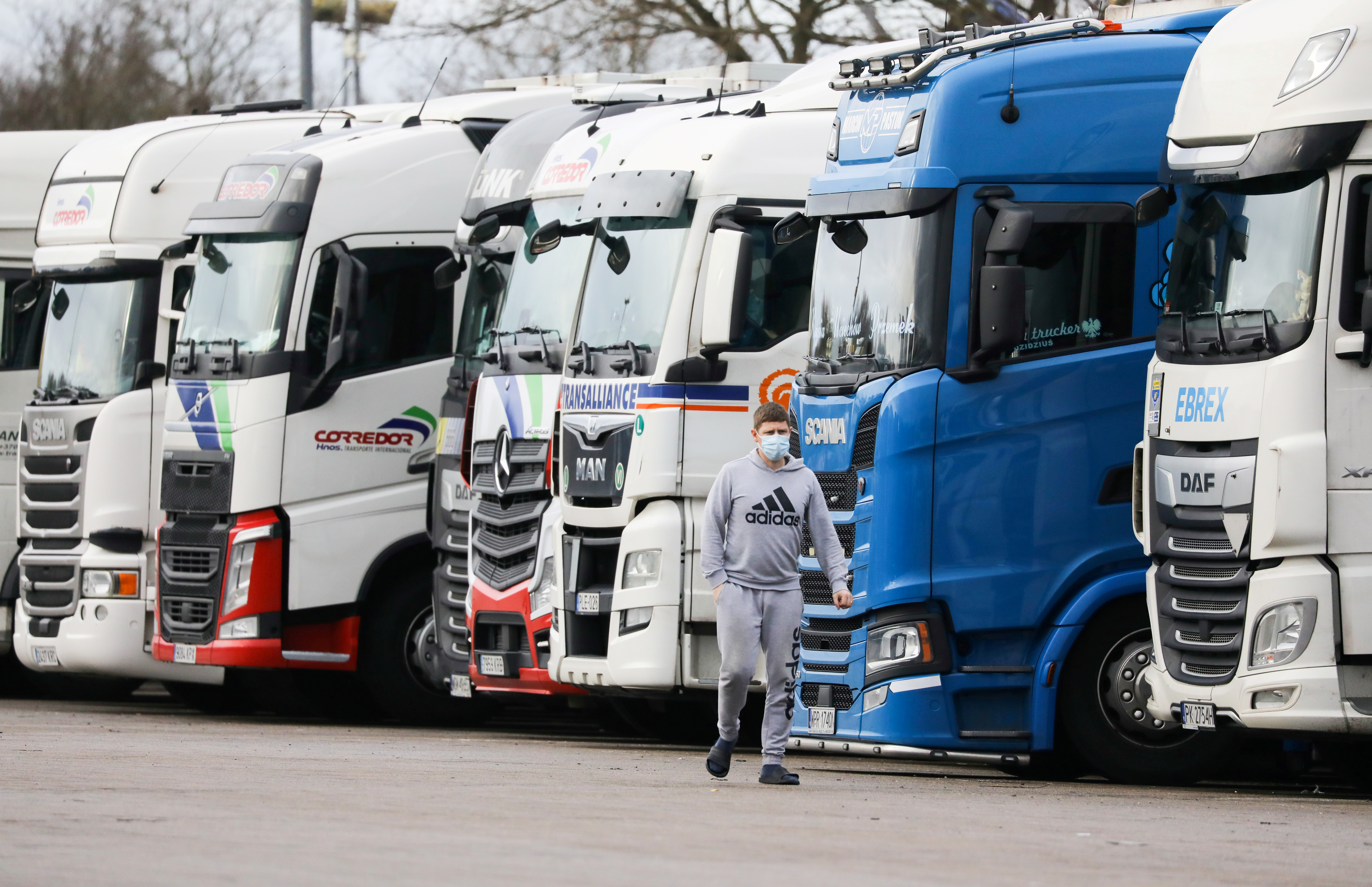 A driver wearing a face mask walks past trucks at Ashford International Truck Stop, as EU countries impose a travel ban from the UK following the coronavirus disease (COVID-19) outbreak, in Ashford, Britain [Simon Dawson/Reuters]