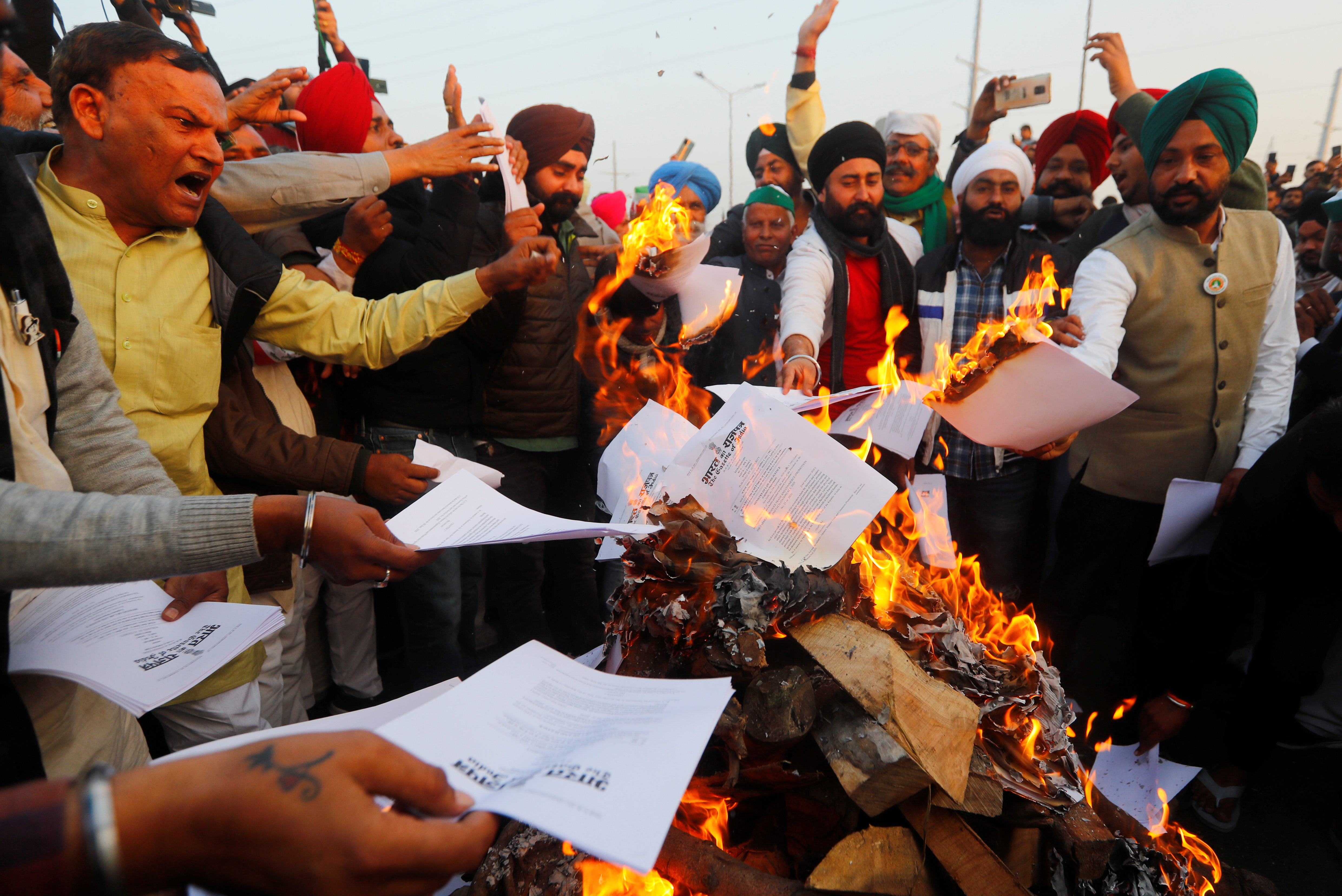 Farmers burn copies of farm laws in a bonfire as they celebrate Lohri festival on January 13, at the Delhi-Uttar Pradesh border in Ghaziabad, India [File: Adnan Abidi/Reuters]