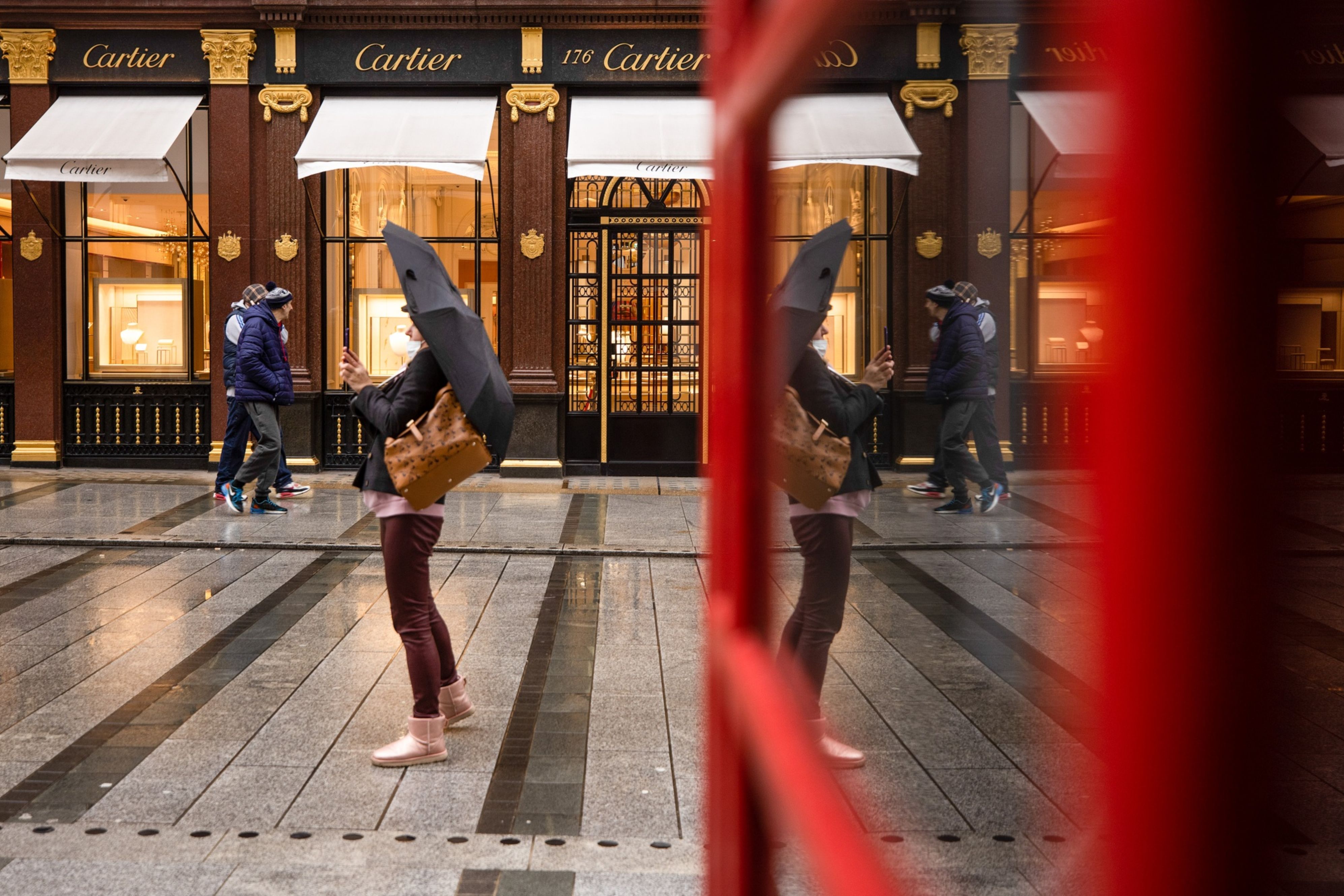 Pedestrians pass empty displays at a closed Cartier luxury watch and jewelry store in London, the United Kingdom, where the young and lowest paid have taken the hardest economic hit during the coronavirus crisis [File: Simon Dawson/Bloomberg]