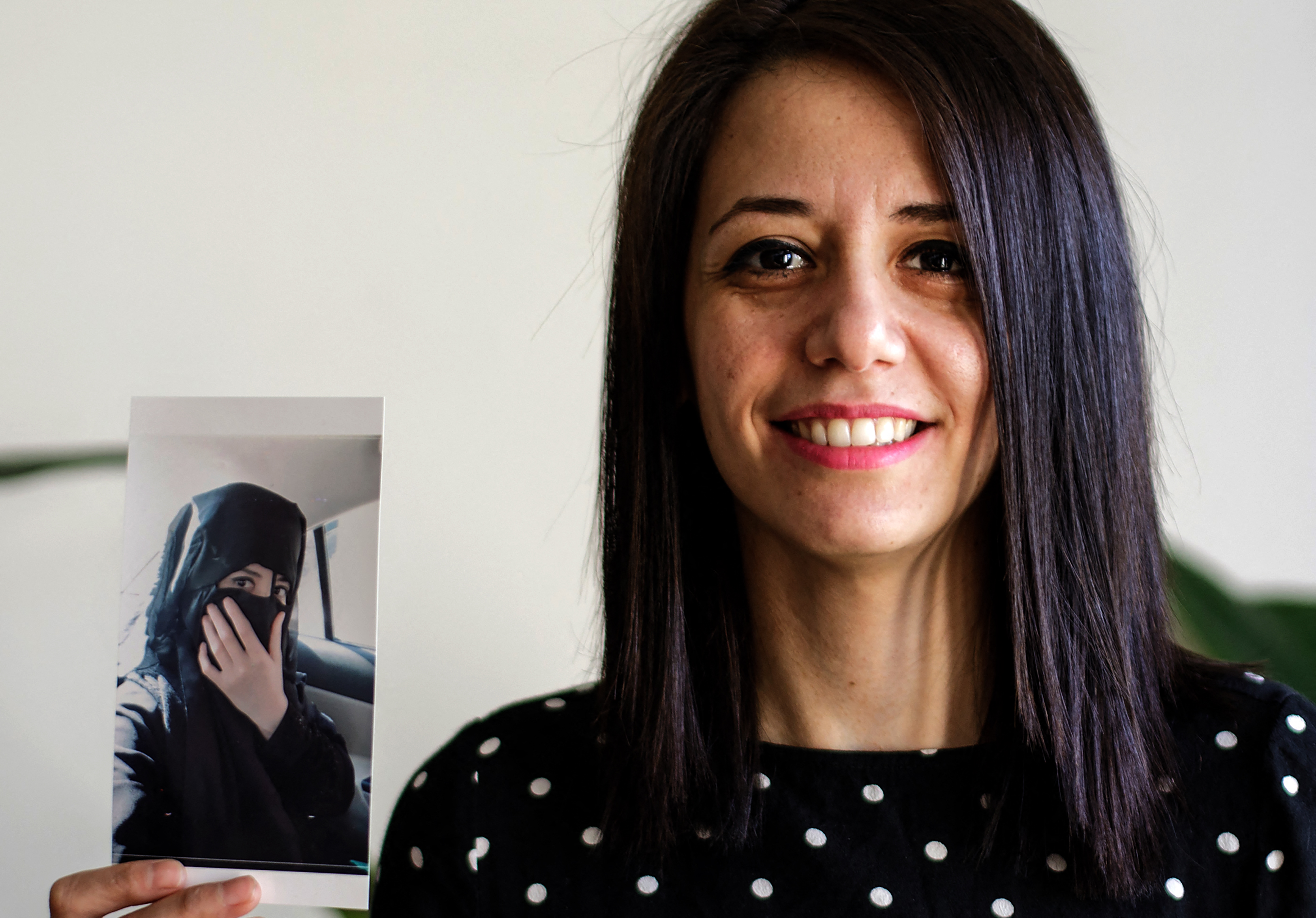 Rukaia Alabadi, a 32-year-old Syrian journalist and refugee, in France&#39;s capital Paris on February 27, 2021. She is holding a photo of herself in 2011 when she was an economics student at al-Furat University in her hometown of Deir Az Zor, eastern Syria. Rukaia arrived in Paris as a refugee in 2018 after escaping threats over her reporting on the reality of life in under ISIL (ISIS) rule. Before that, she had been detained for months over her work as a media activist. [Sameer Al-Doumy/AFP]
