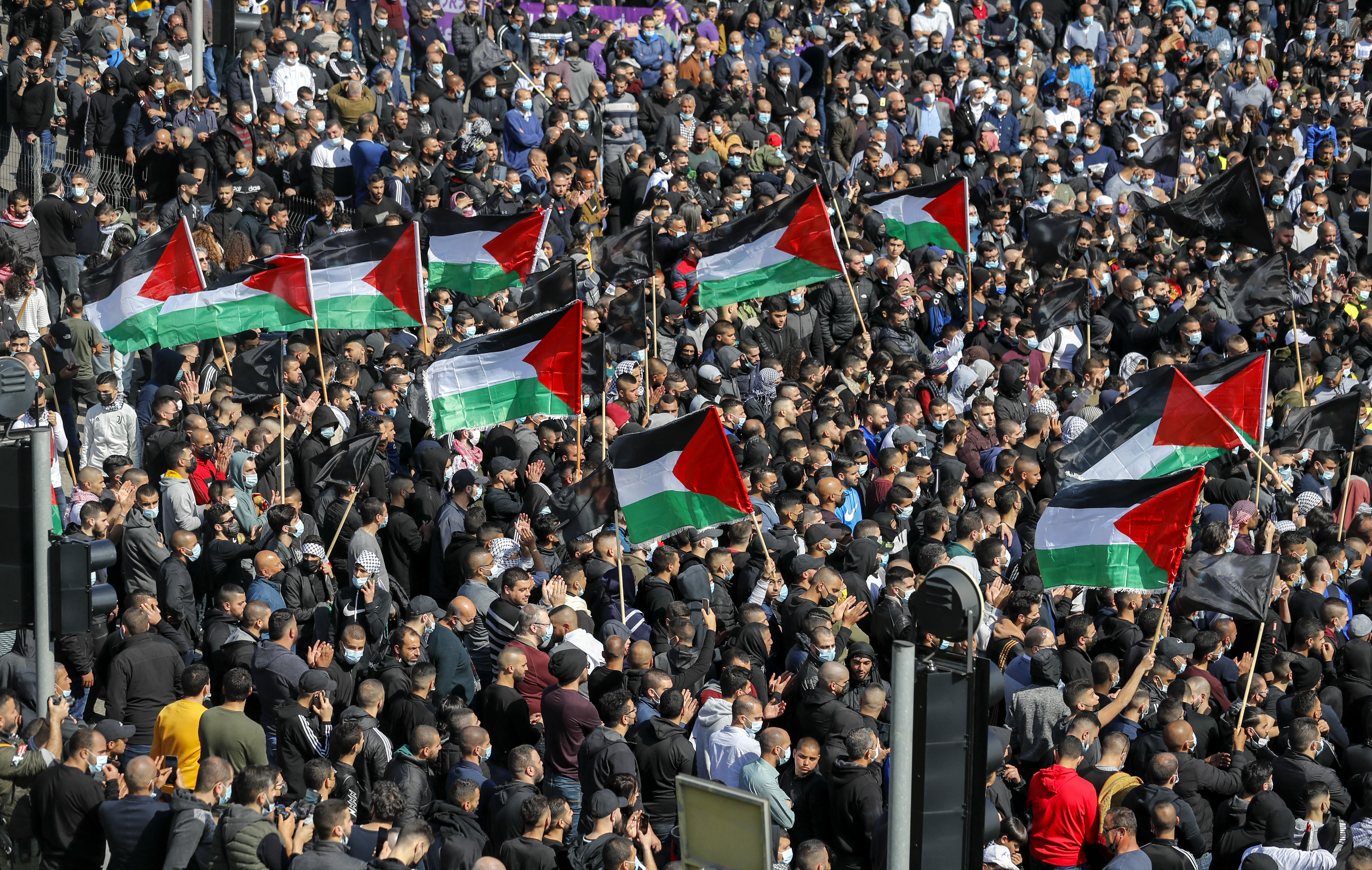 Flags wave during a demonstration by Palestinians in the city of Umm al-Fahm in March against organised crime [Ahmad Gharabli/AFP]