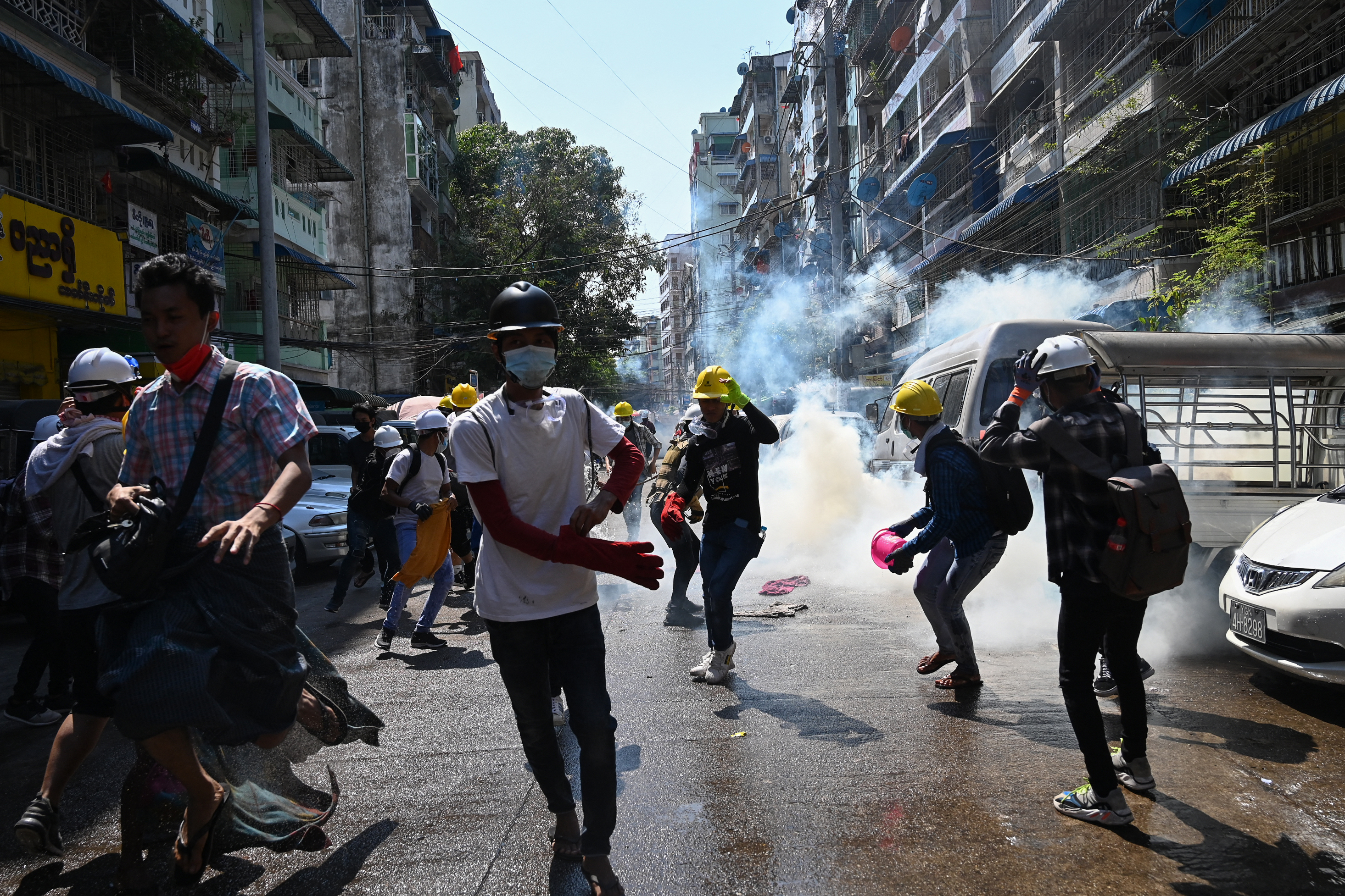 Protesters react after tear gas is fired by police during a demonstration against the military coup in Yangon on March 7, 2021 [File: Photo by STR/AFP]