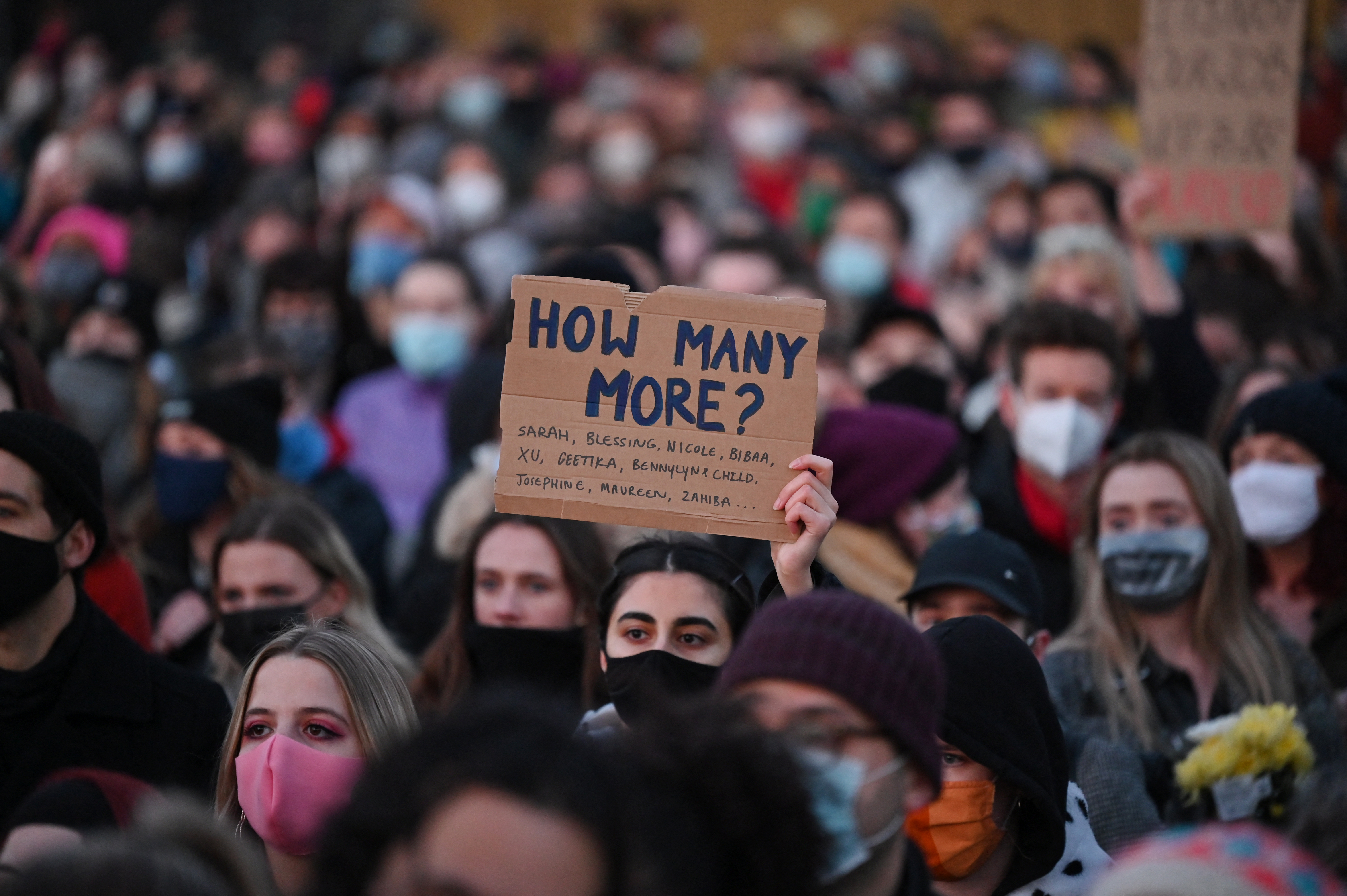 Well-wishers, one with a placard that reads &#039;How many more?&#039;, gather at a vigil in honour of murder victim Sarah Everard, in Clapham, south London, England on March 13, 2021 [Justin Tallis/AFP]