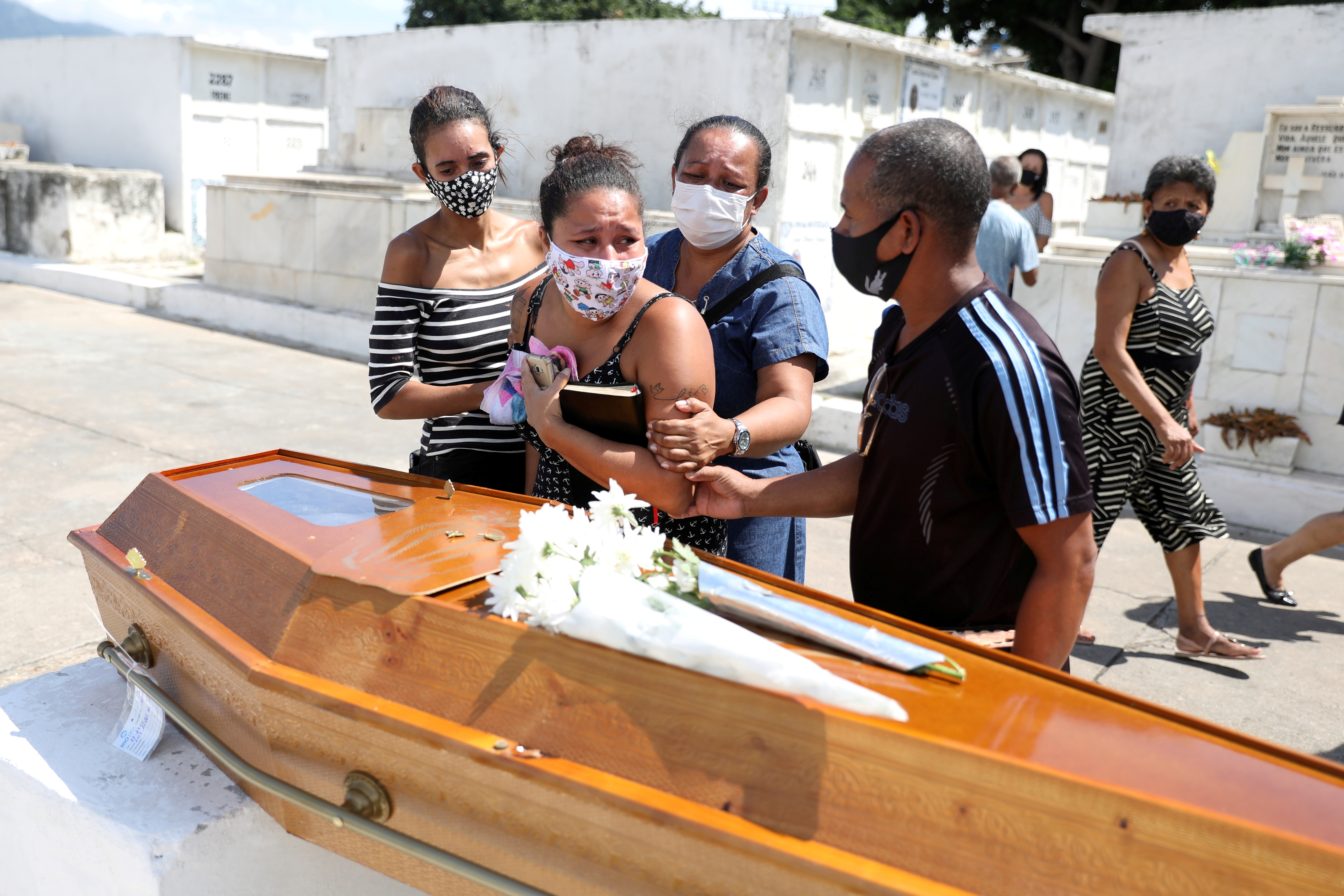 Relatives of Luiz Alves, 63, who died from COVID-19, react at his funeral at Inhauma cemetery in Rio de Janeiro, Brazil on March 10 [Pilar Olivares/Reuters]
