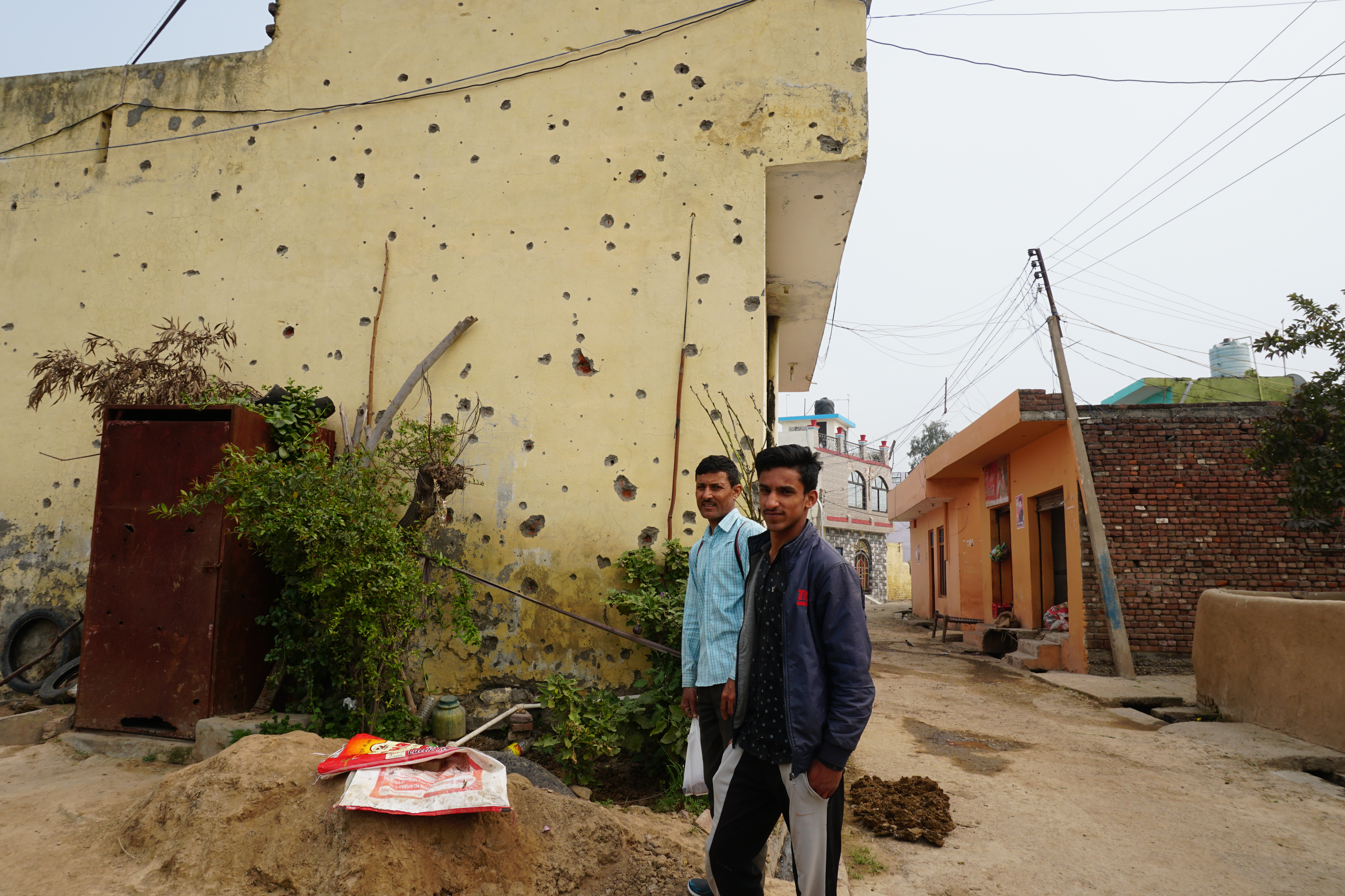 A wall in Suchetgarh village was hit by multiple shells in violation of the India-Pakistan ceasefire [Rifat Fareed/Al Jazeera]