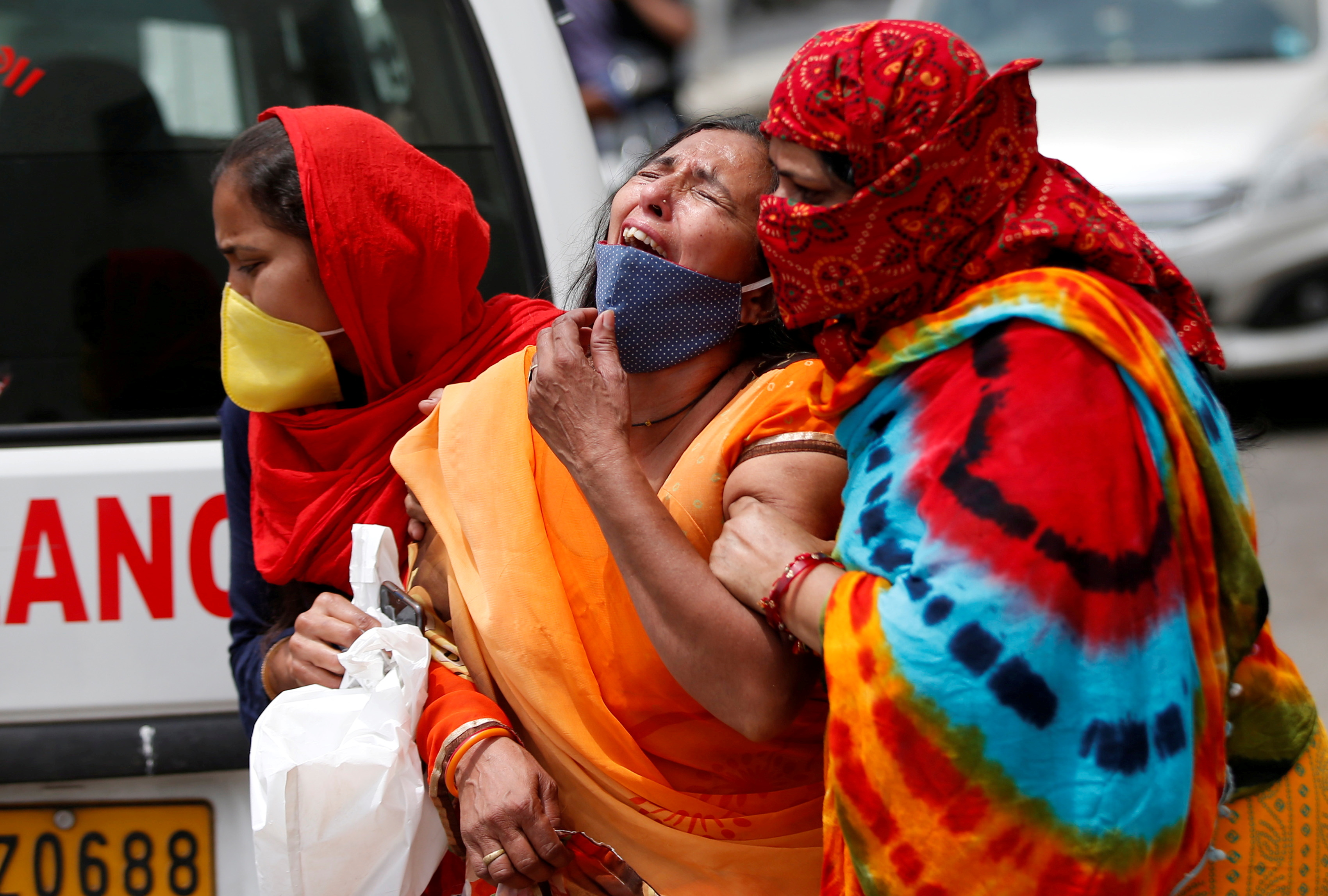 In this file photo from April 20, a woman is consoled after her husband died due to COVID-19 in Ahmedabad, India [File: Amit Dave/Reuters]