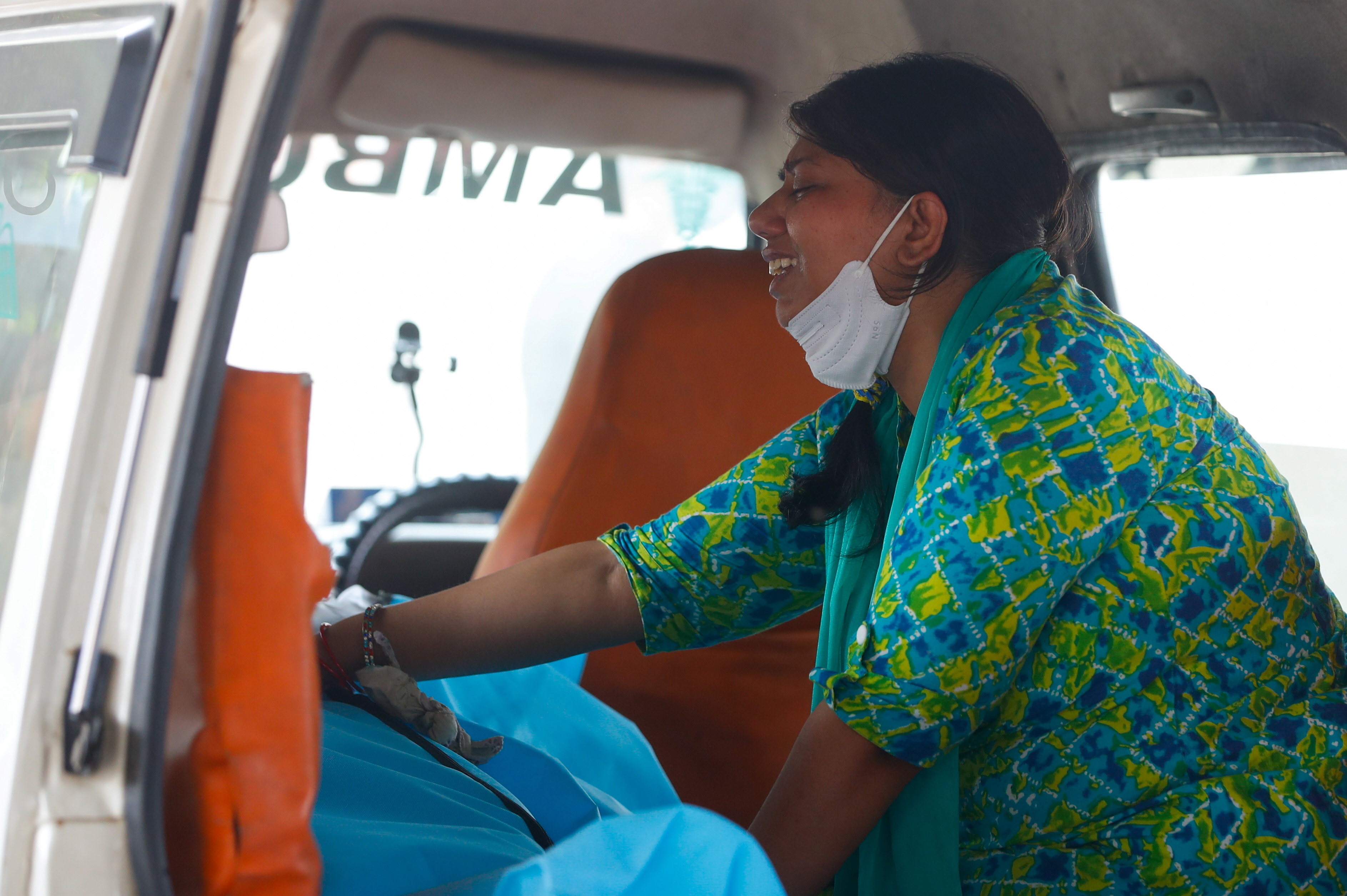 Aanchal Sharma cries over the body of her husband, who died from COVID-19 inside an ambulance in New Delhi [Adnan Abidi/Reuters]