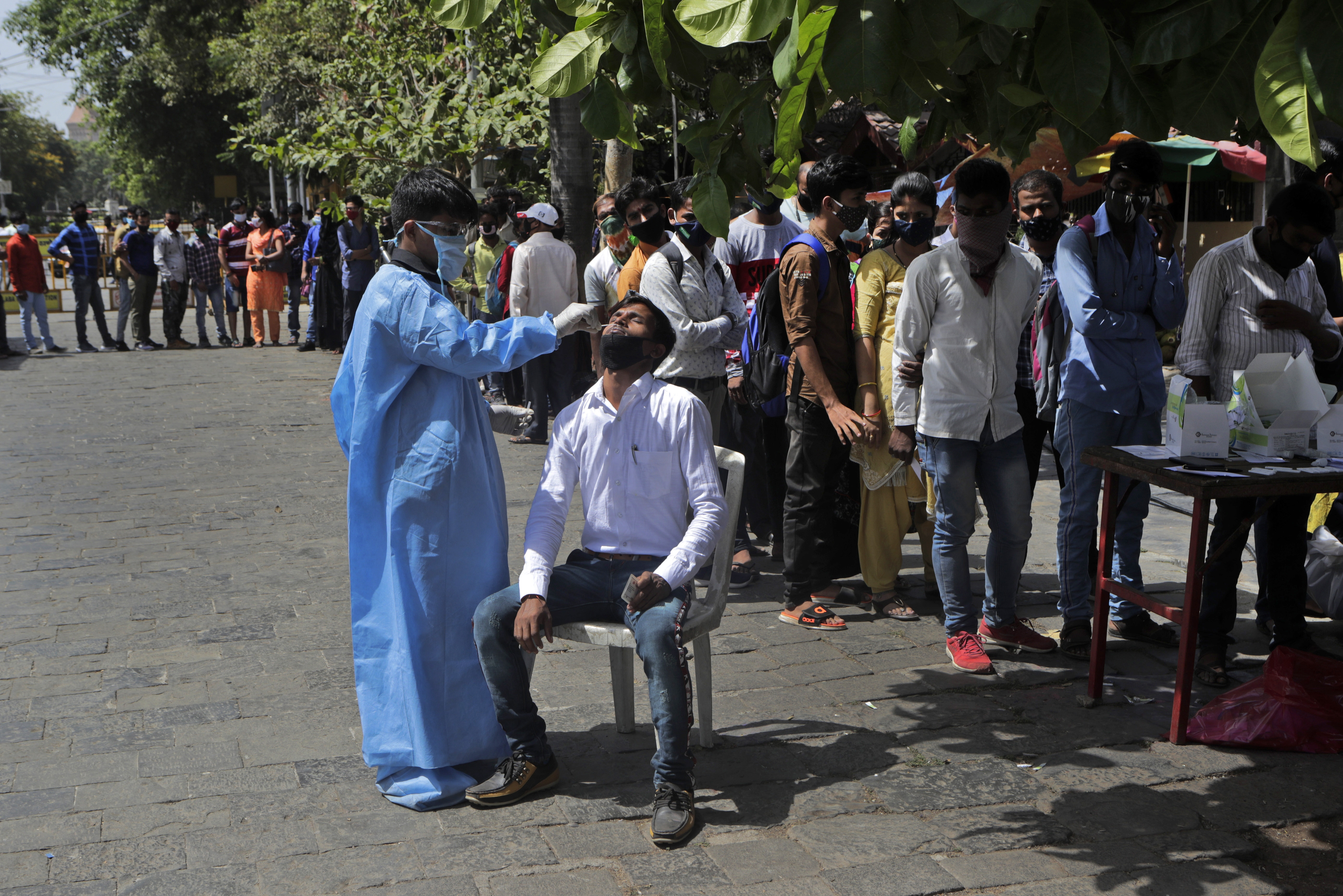 People wait in a queue to get their swab sample taken to test for COVID-19 at a camp outside the landmark Gateway of India in Mumbai. [Rajanish Kakade/AP Photo]