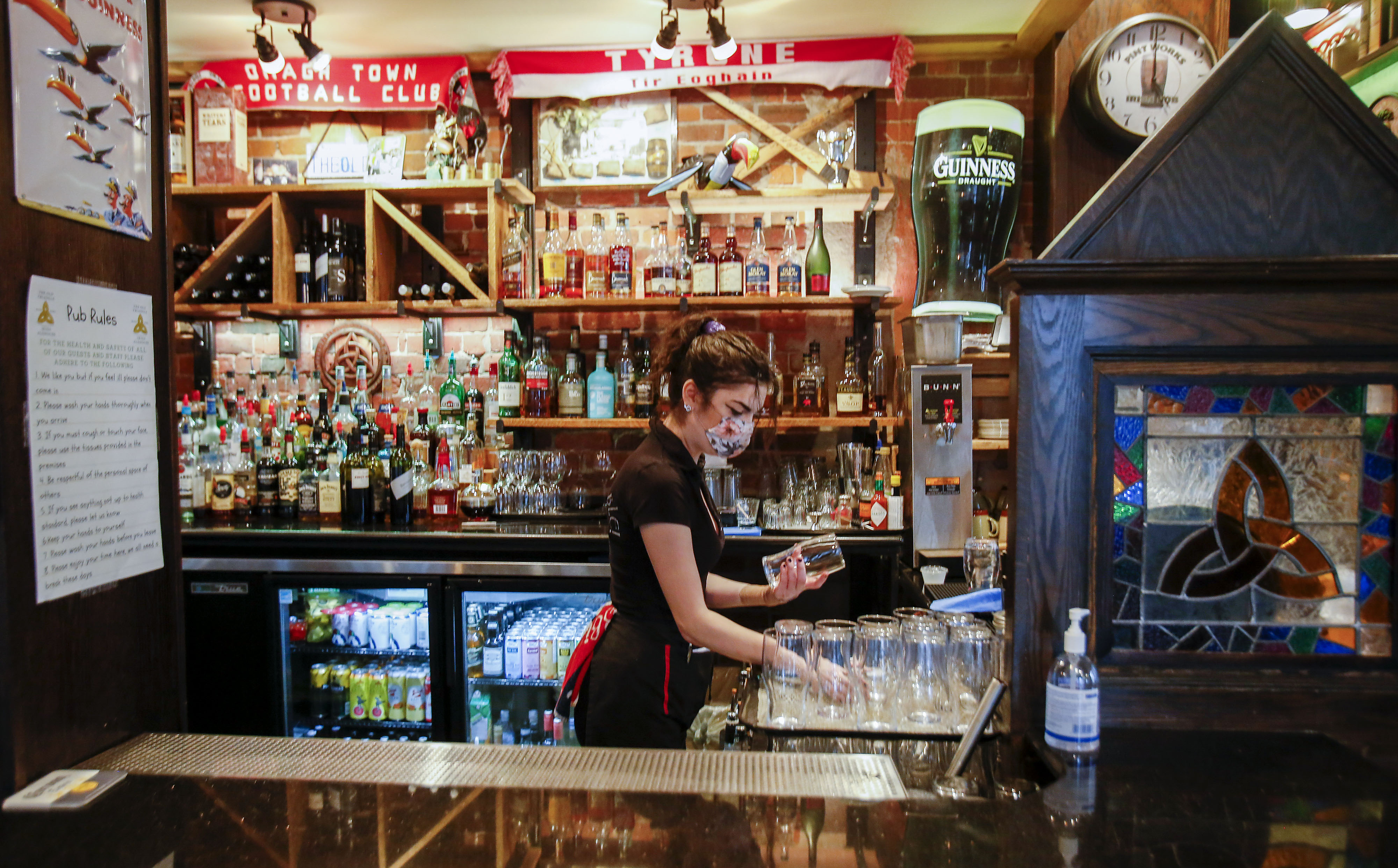 A bartender wearing a protective mask arranges glasses at a bar in Halifax, Nova Scotia, on Monday, November 16, 2020 [File: Tim Krochak/Bloomberg via Getty Images]