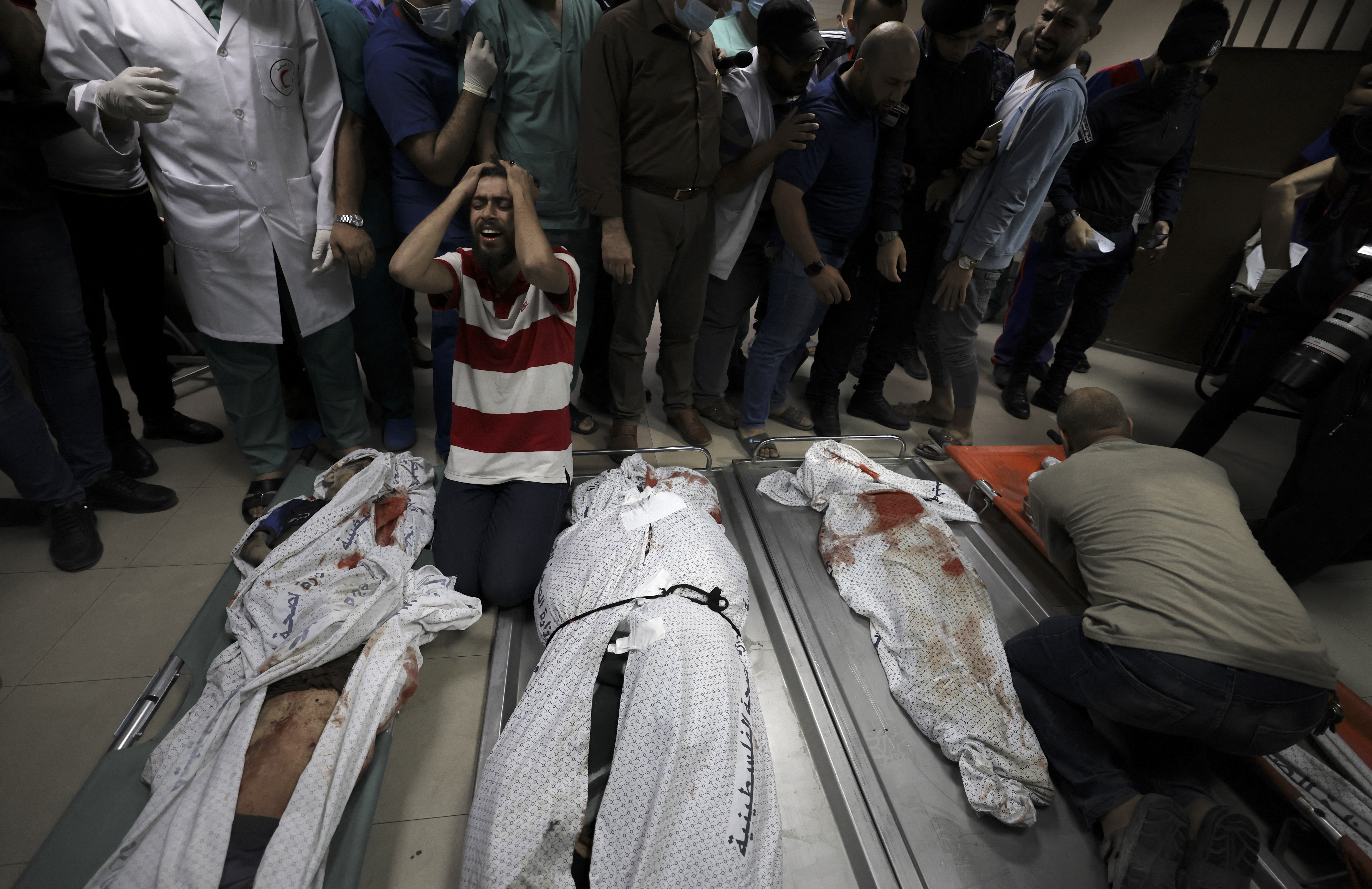Relatives of the Abu Hatab family mourn over the bodies of their family members in al-Shifa Hospital [Mahmud Hams/AFP]