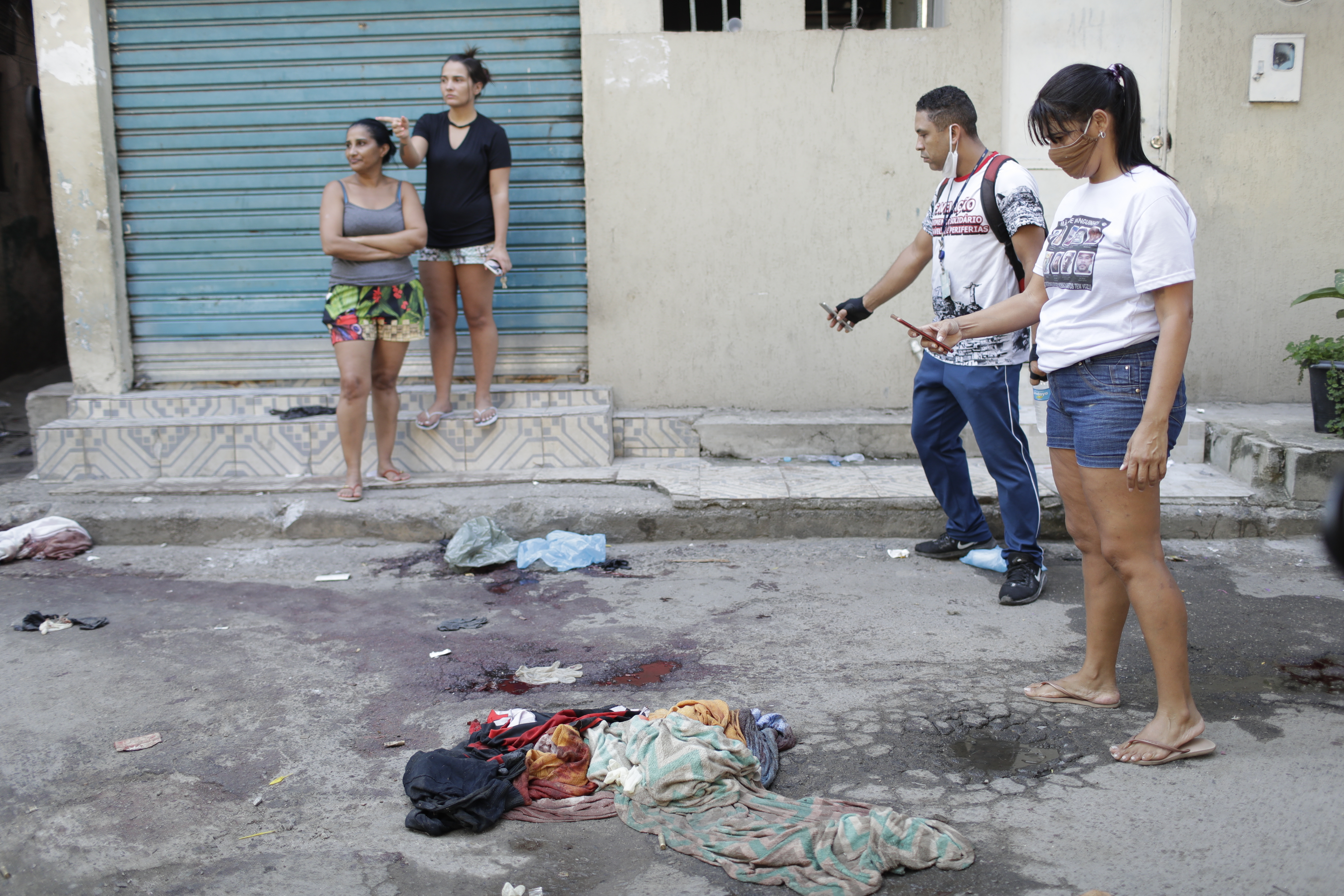 Residents take pictures of blood on the street after a police operation targeting suspected drug traffickers in the Jacarezinho favela of Rio de Janeiro on Thursday [Silvia Izquierdo/AP]