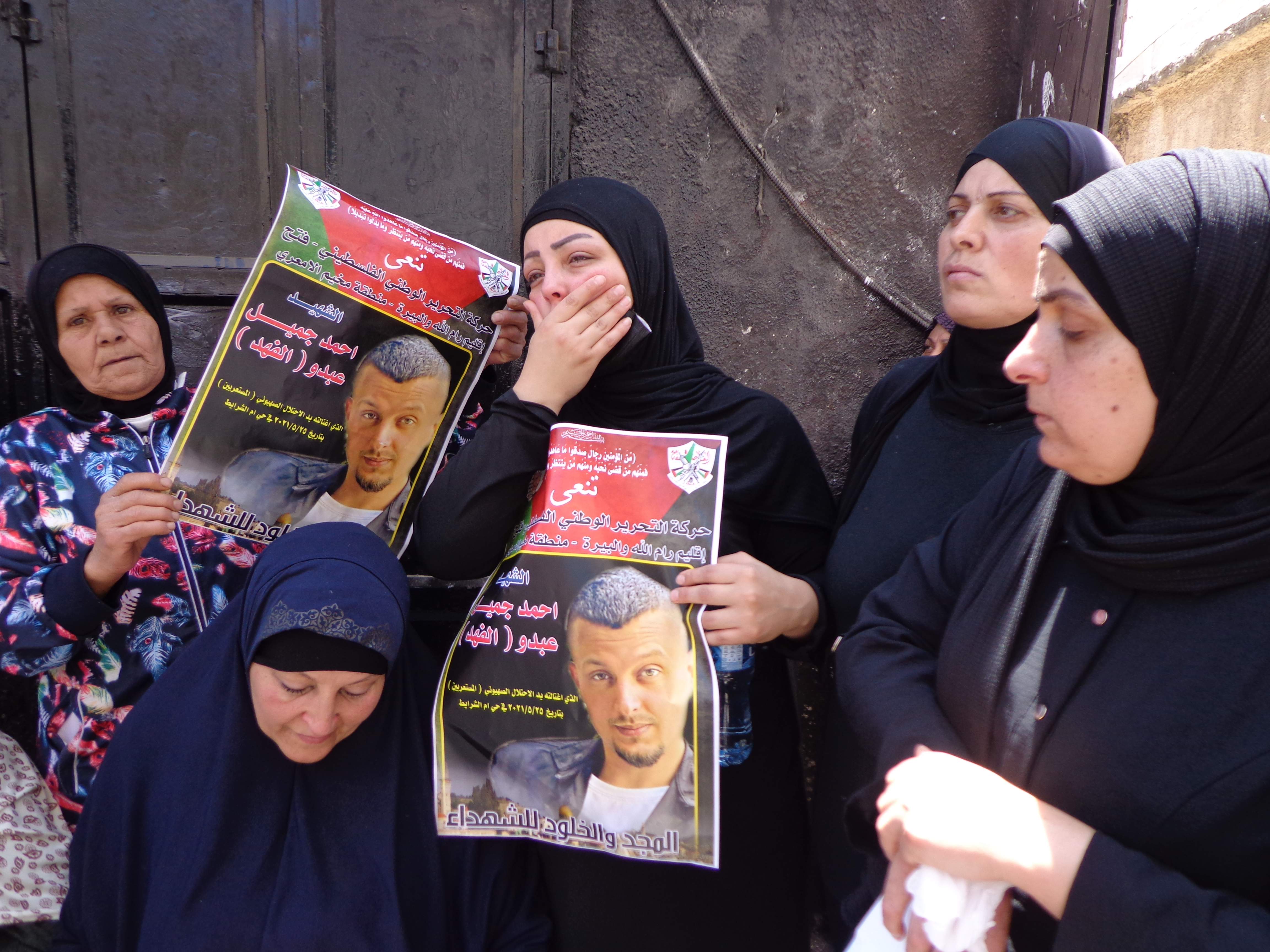 Ahmed Fahd&#39;s sister Roseanne cries at his funeral while holding a poster at the al-Amari refugee camp near Ramallah [Al Jazeera]