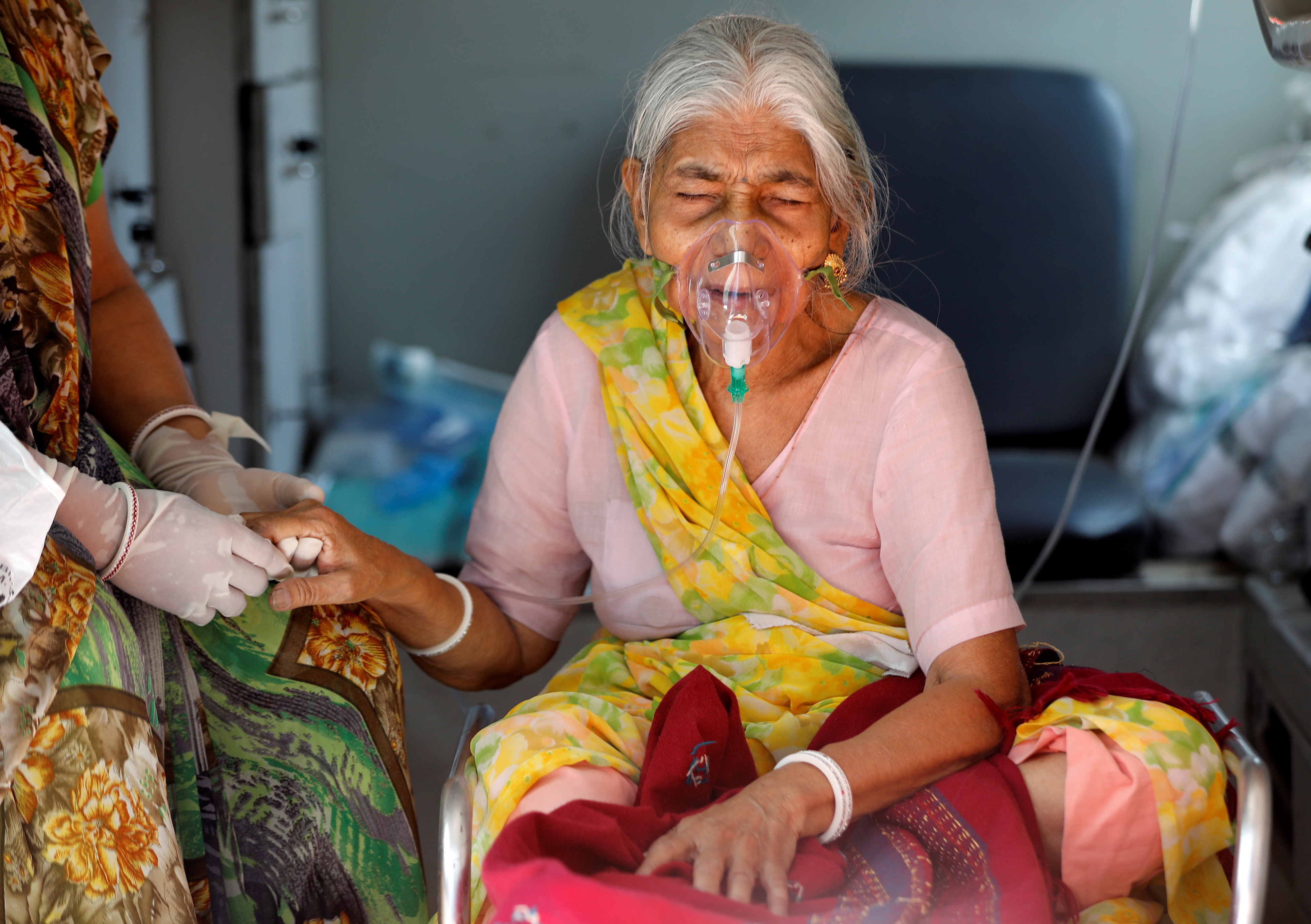 Lilaben Gautambhai Modi, 80, wearing an oxygen mask, sits inside an ambulance as she waits to enter a COVID-19 hospital for treatment in Ahmedabad, India [Amit Dave/Reuters]