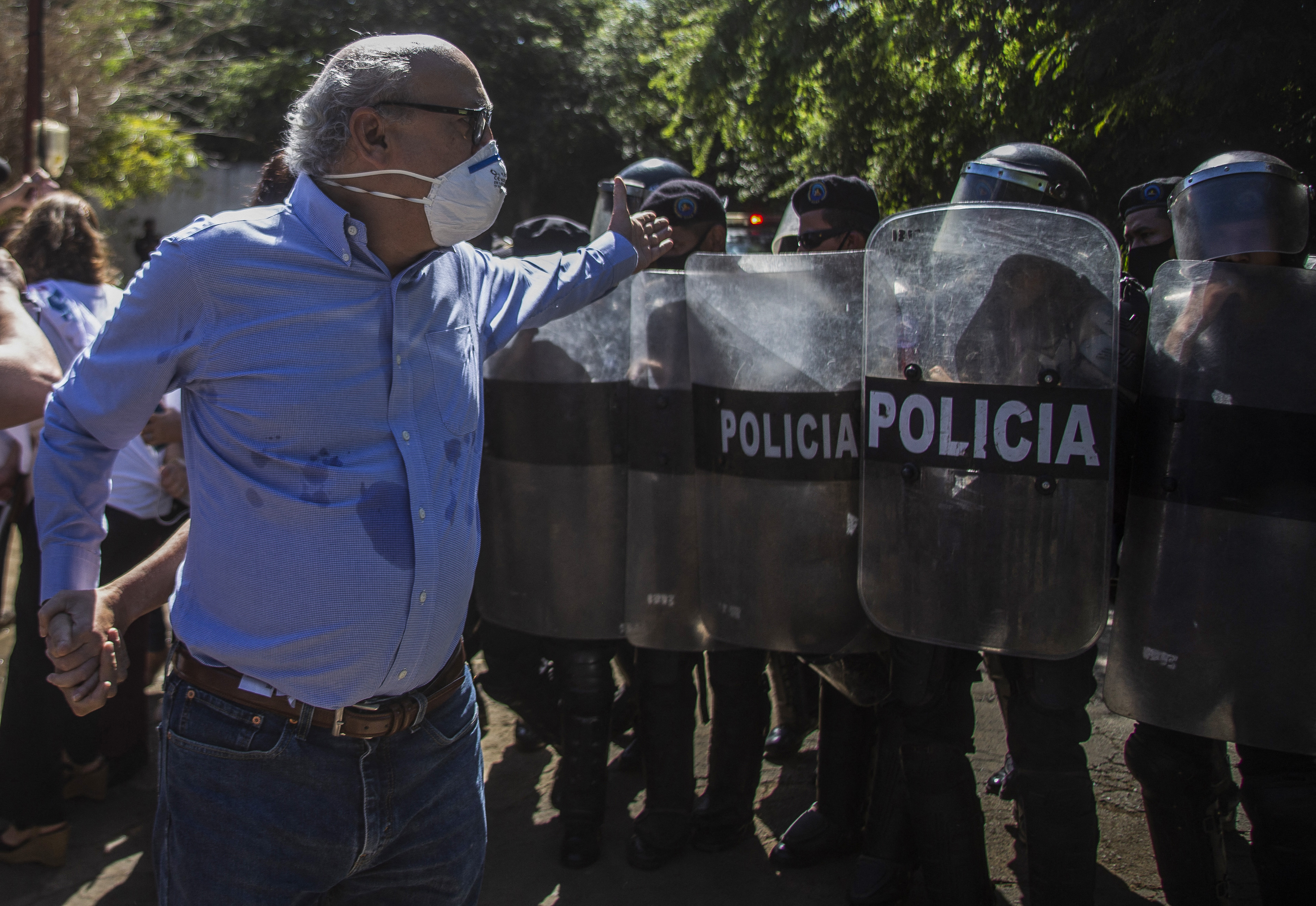 Nicaraguan journalist Carlos Fernando Chamorro, of Confidencial and Esta Semana news media, is pushed away by riot police outside El Confidencial offices in Managua, Nicaragua on December 14, 2020 - he fled Nicaragua Monday June 21, 2021 [File: STR/AFP]