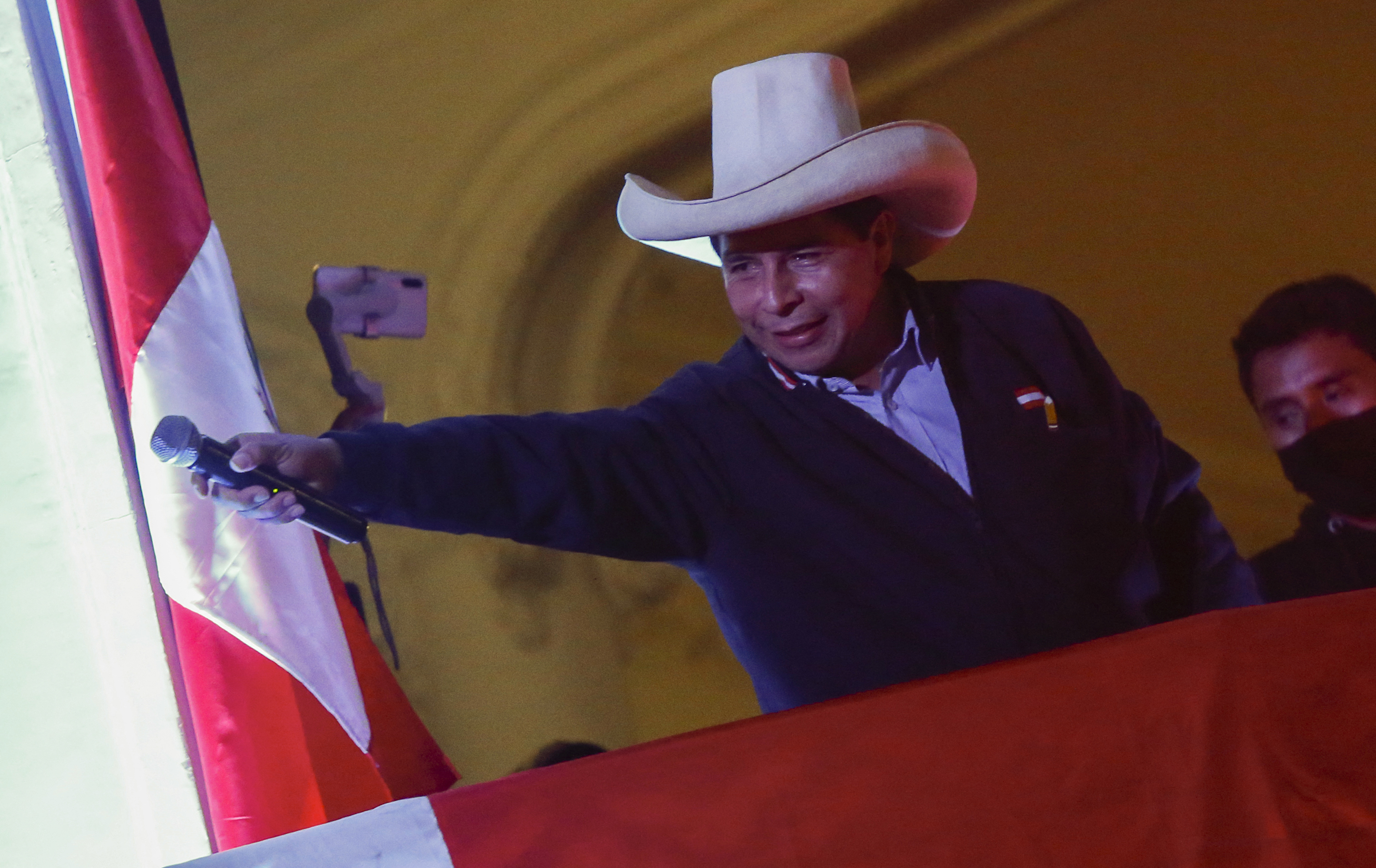 Peru&#39;s left-wing presidential candidate Pedro Castillo gestures to his supporters from the balcony of his party headquarters in Lima on June 10 [Gian Masko/AFP]