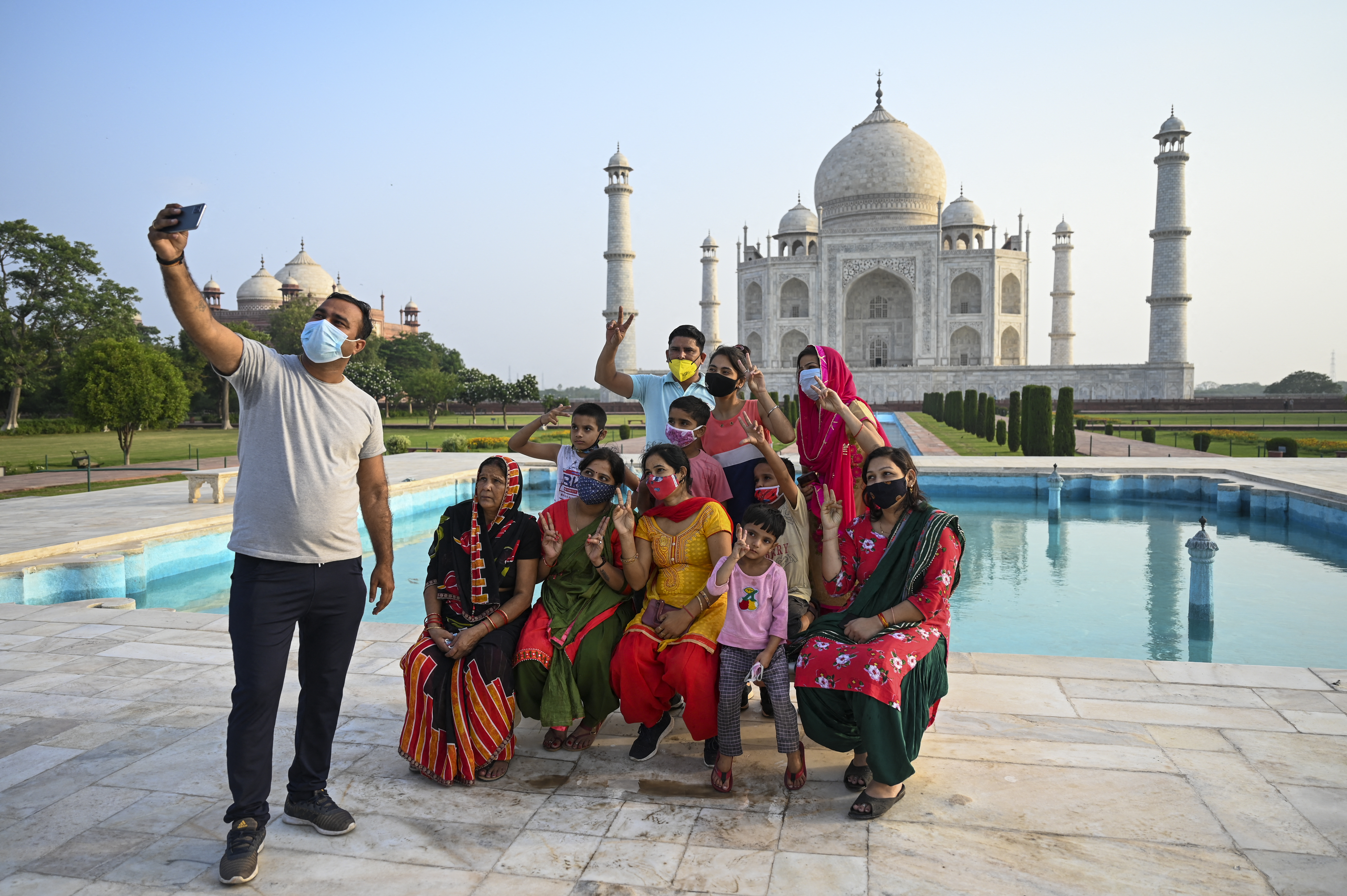 A group of tourists take souvenir photos at the Taj Mahal after it reopened to visitors as authorities eased coronavirus restrictions [Money Sharma/AFP]