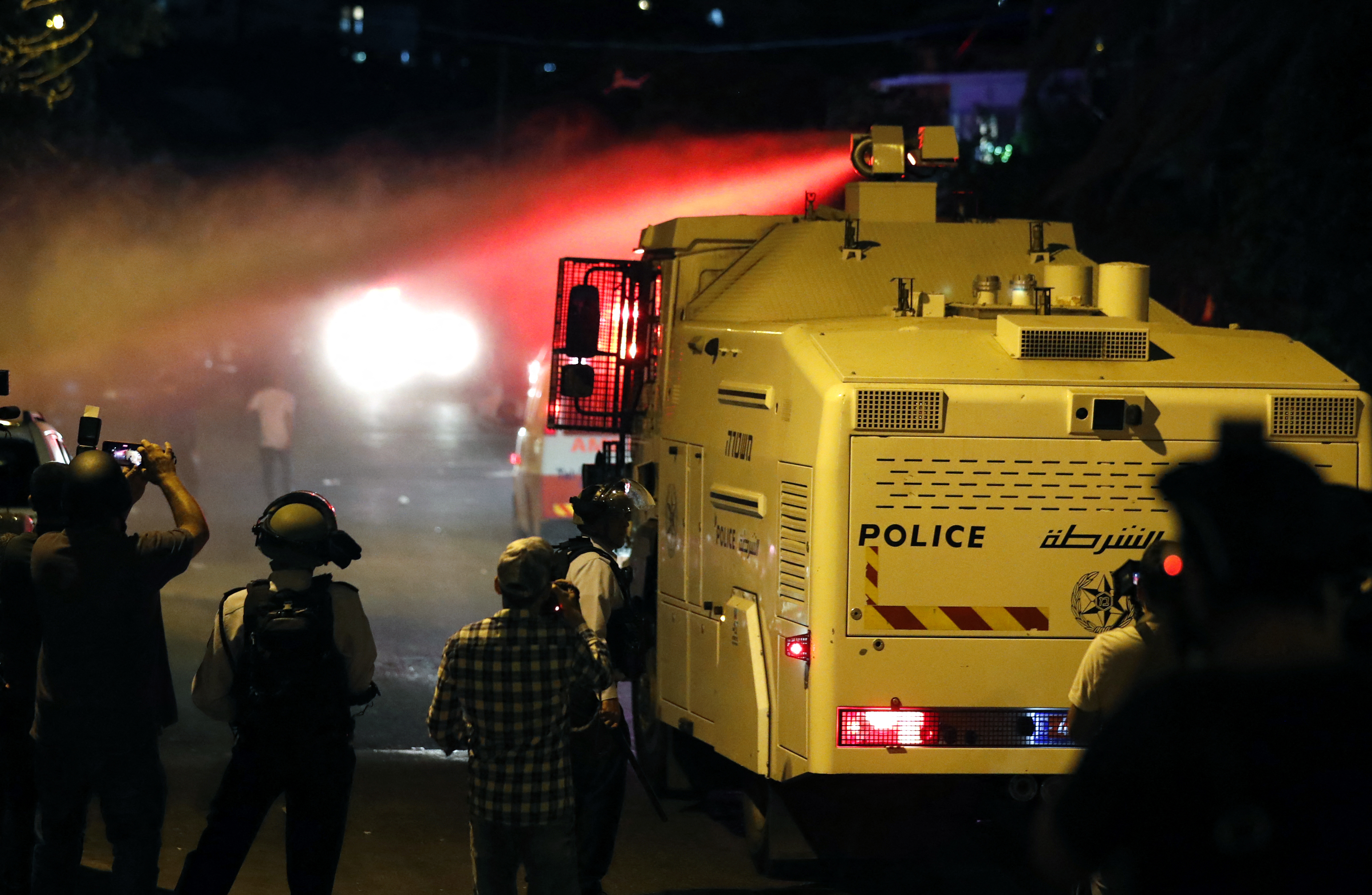 Israeli security forces spray Palestinian protesters with skunk water in the east Jerusalem neighbourhood of Sheikh Jarrah on June 21, 2021 [Ahmad Gharabli/AFP]