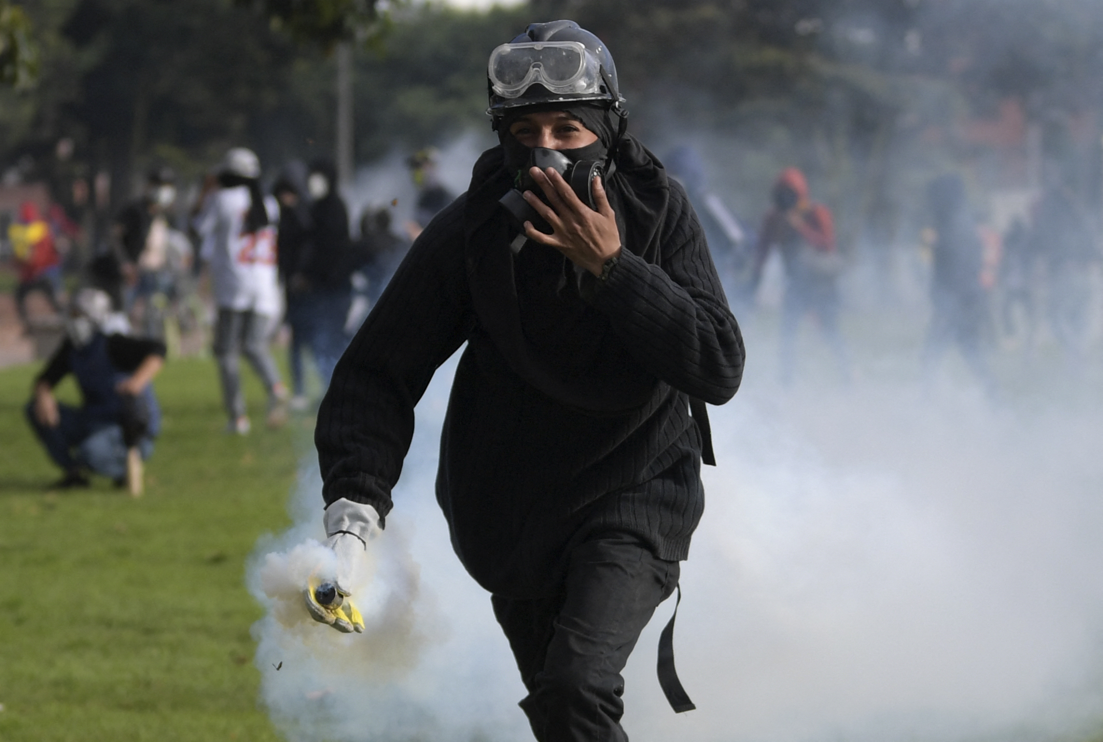 A demonstrator holds a tear gas canister during clashes with riot police in Suba neighbourhood, Bogota. [Raul Arboleda/AFP]
