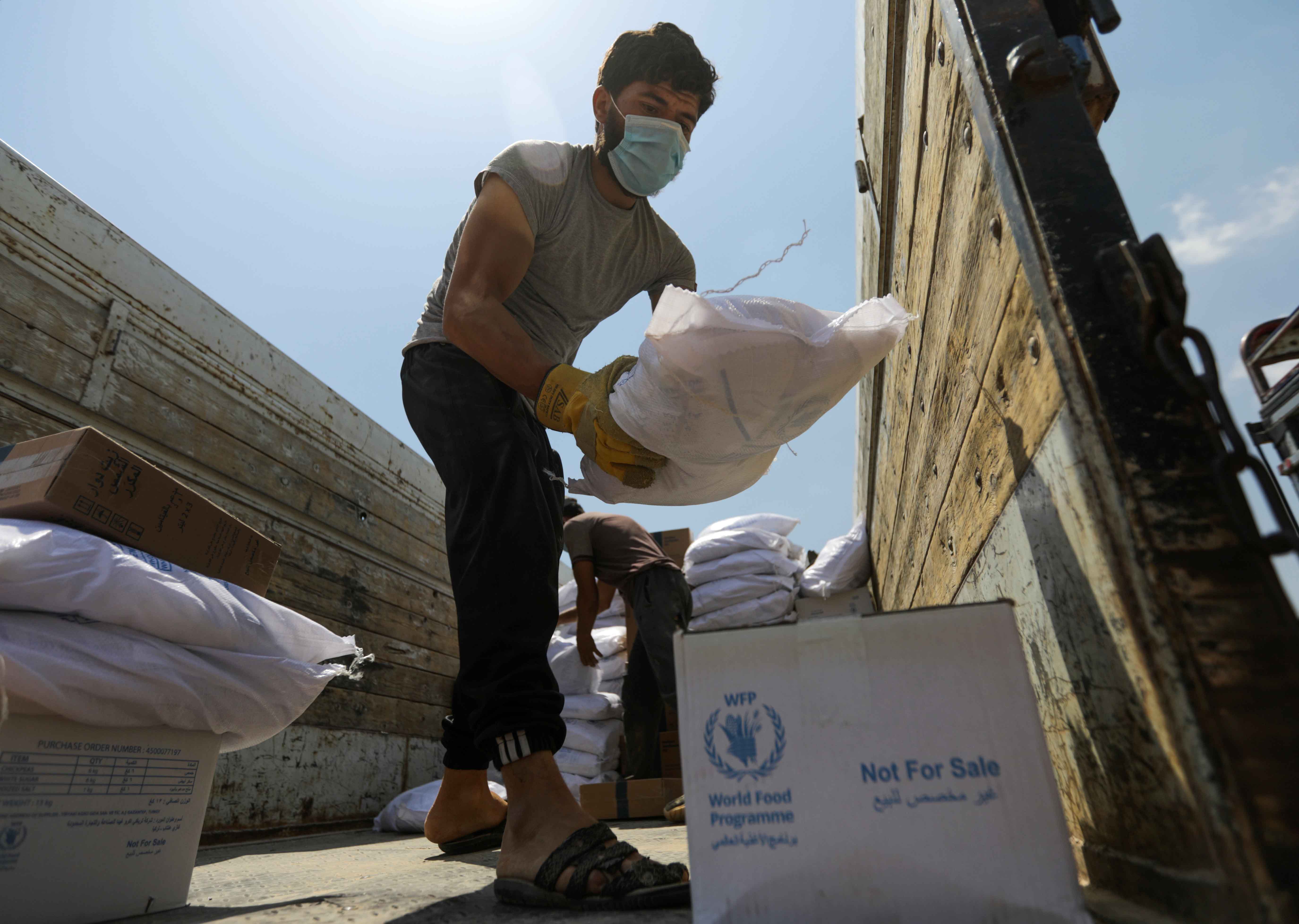 A worker unloads bags and boxes of humanitarian aid from the back of a truck in the opposition-held Idlib, Syria on June 9, 2021 [Reuters/Khalil Ashawi]