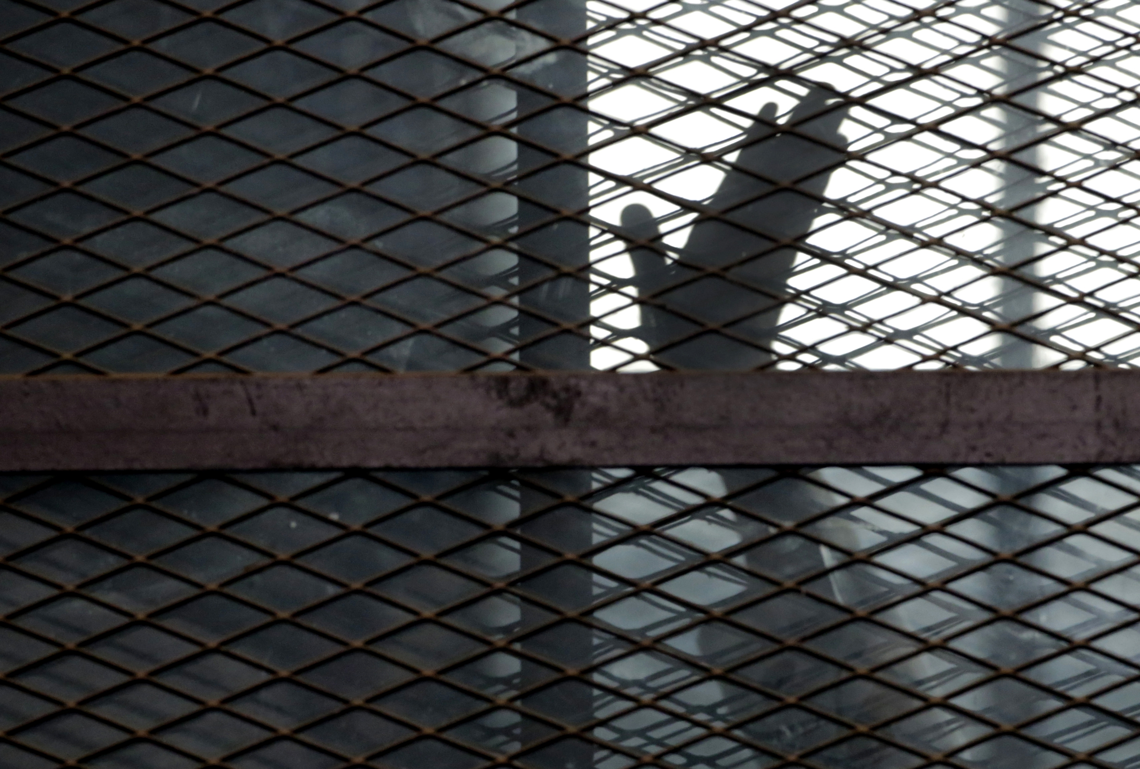 A member of the Muslim Brotherhood waves his hand from a defendant&#39;s cage in a courtroom in Torah prison, southern Cairo, Egypt [File: Amr Nabil/AP Photo]