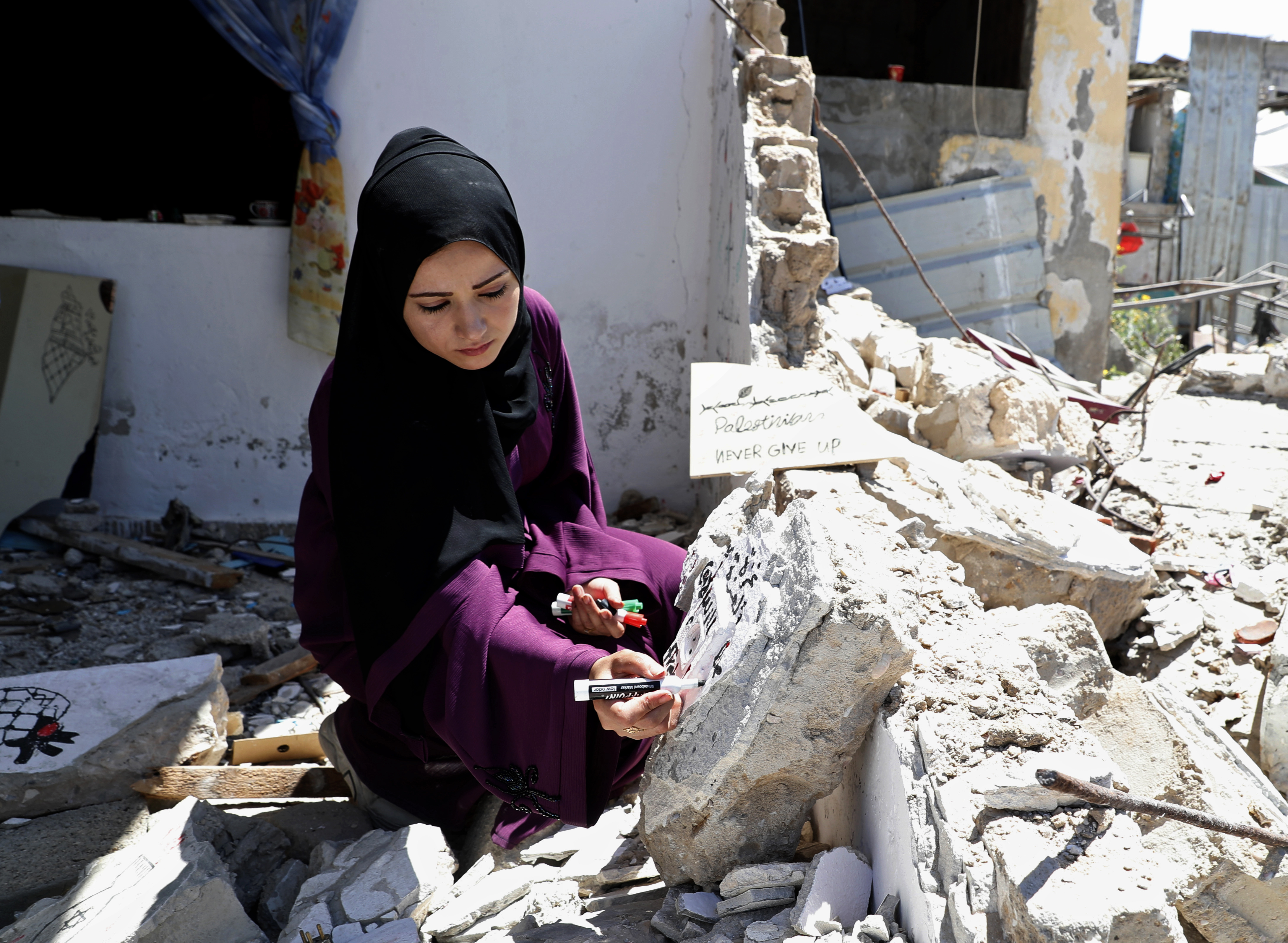 Artist Saja Moussa draws on broken tiles from her family&#39;s house in Rafah, southern Gaza Strip, damaged by Israeli bombing in May [Adel Hana/AP Photo]