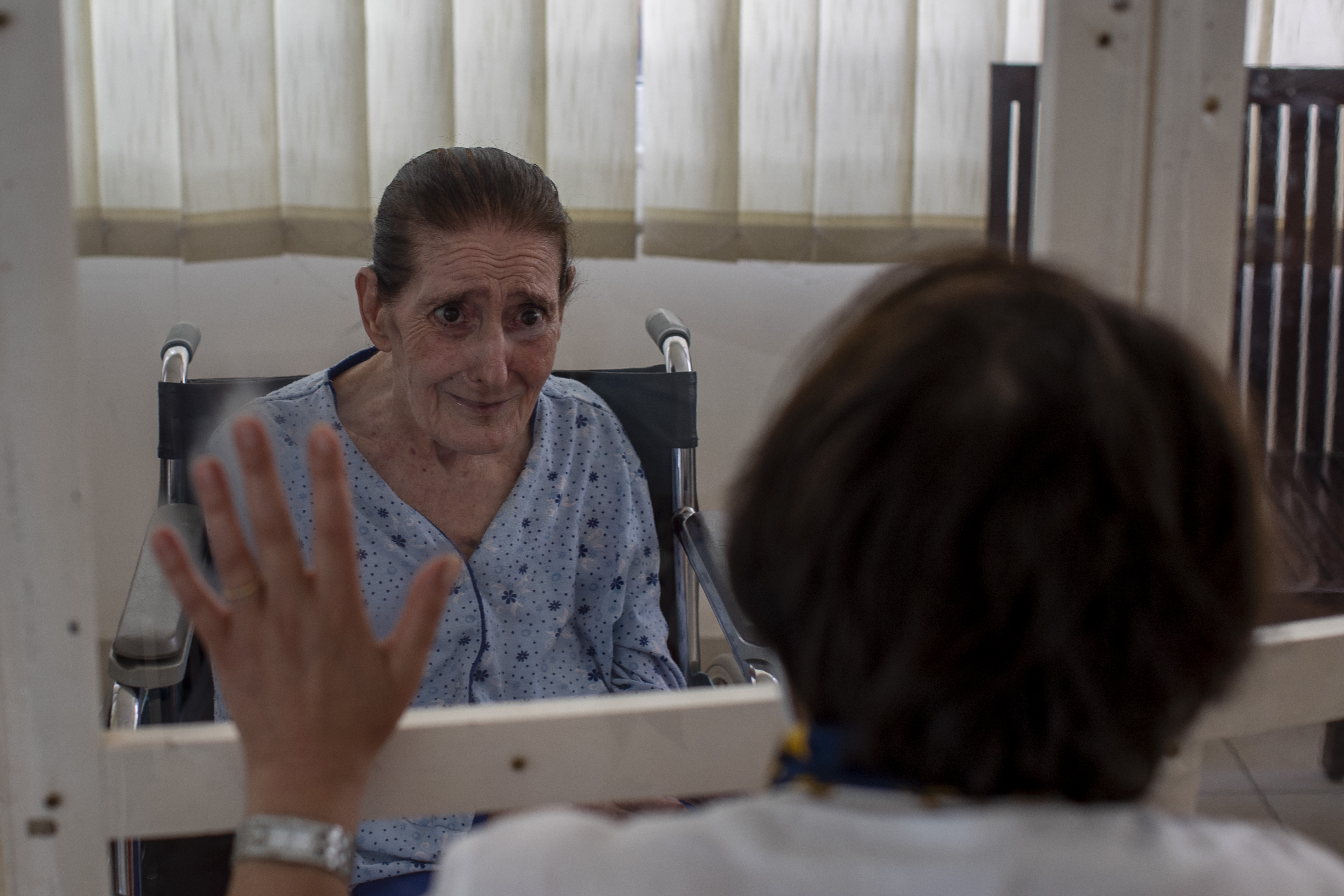 Rafka Nassim, 71, left, meets with her daughter Claudette Rizk through a plastic barrier to avoid contracting the coronavirus at the Social Services Medical Association, a rehabilitation hospital and nursing home in the northern city of Tripoli. [Hassan Ammar/AP Photo]
