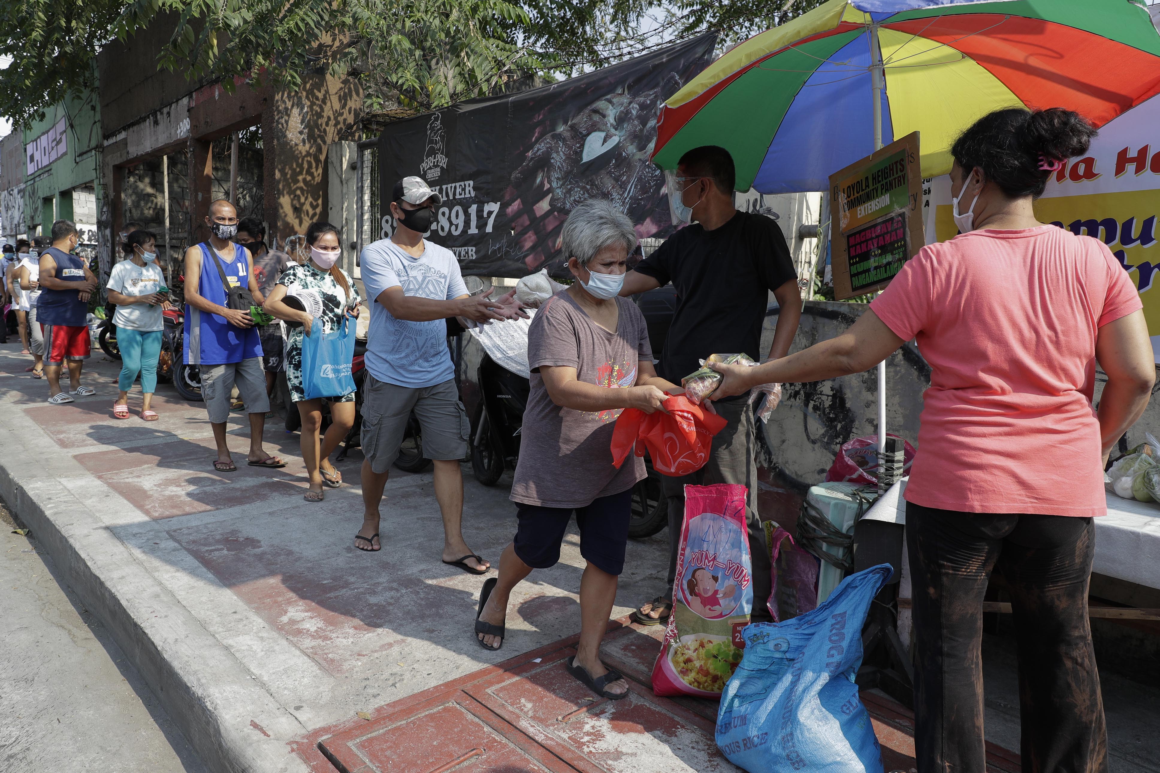 Residents receive free food at a &#39;community pantry&#39;. The pantries have been popping up across the capital to help people cope during the government lockdown to curb the spread of the coronavirus in Quezon City, Philippines on April 29, 2021 [File: Aaron Favila/AP]