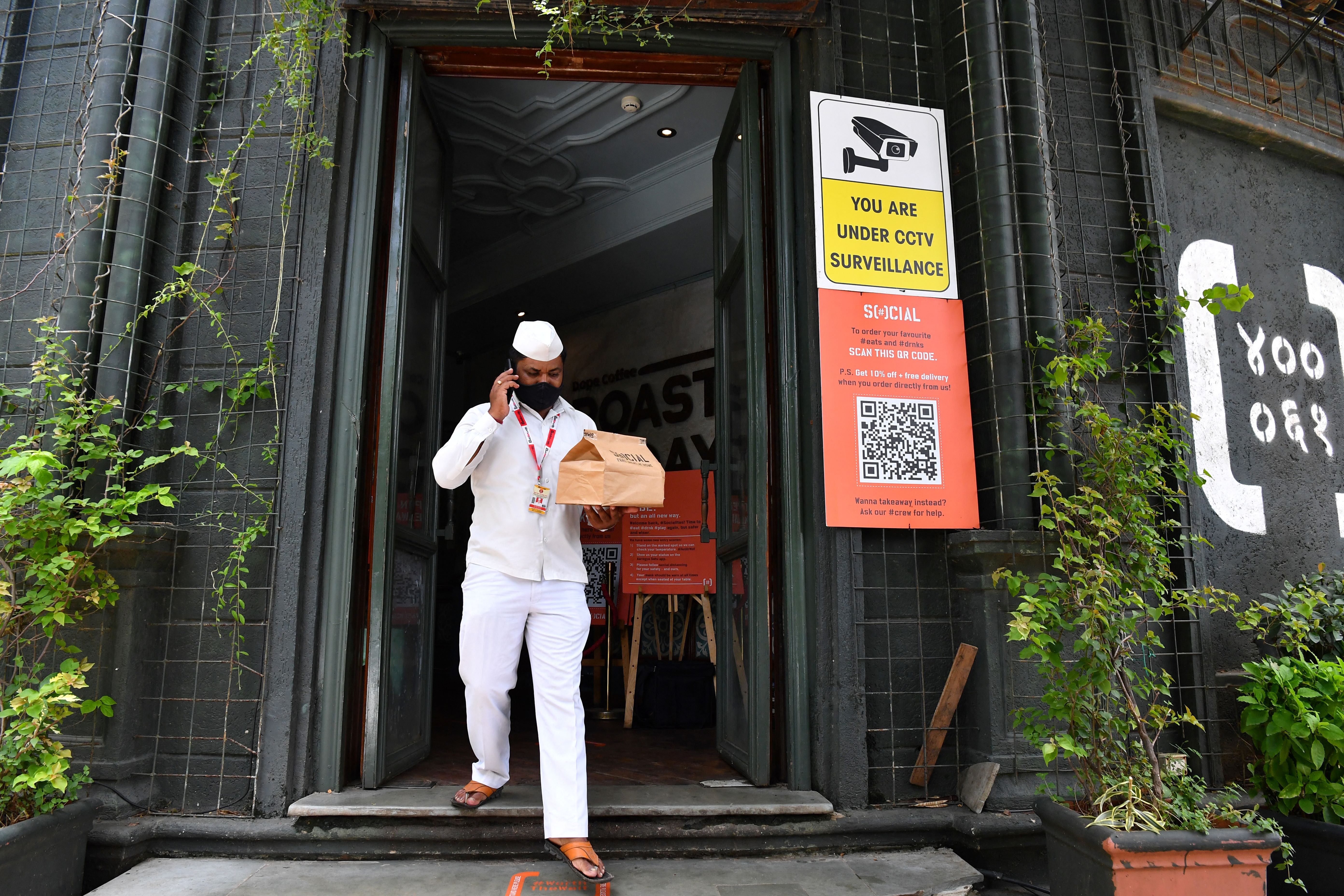 In this photo taken on June 22, 2021 &#39;Dabbawala&#39; Sunil Shinde speaks on his phone after collecting an order from a restaurant in Mumbai [Indranil Mukherjee/AFP]