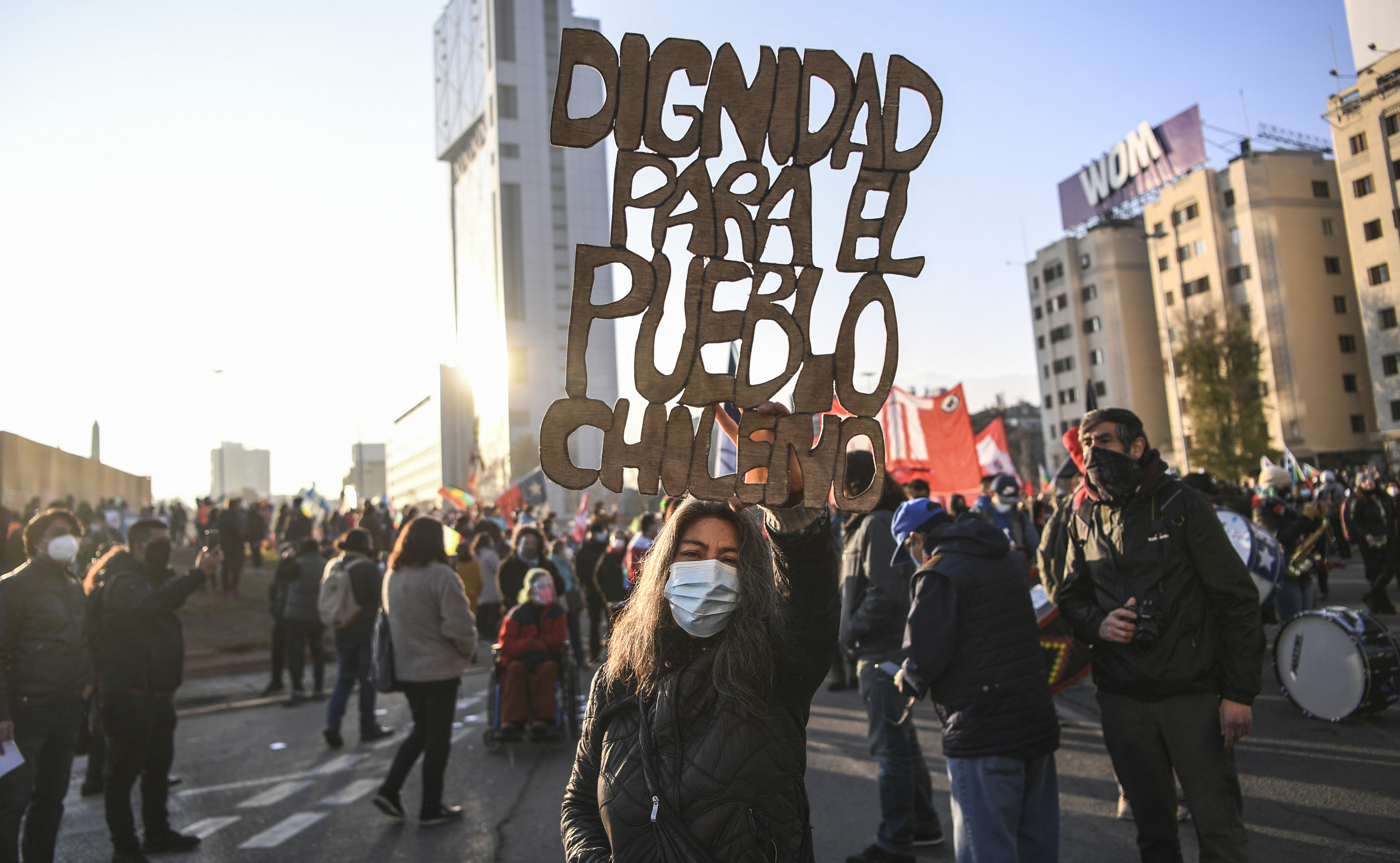 A demonstrator holds a sign reading &#39;Dignity for Chilean people&#39; during a march towards the Chilean National Congress where the Constituent Assembly will be inaugurated in Santiago, on July 4 [Martin Bernetti/AFP]