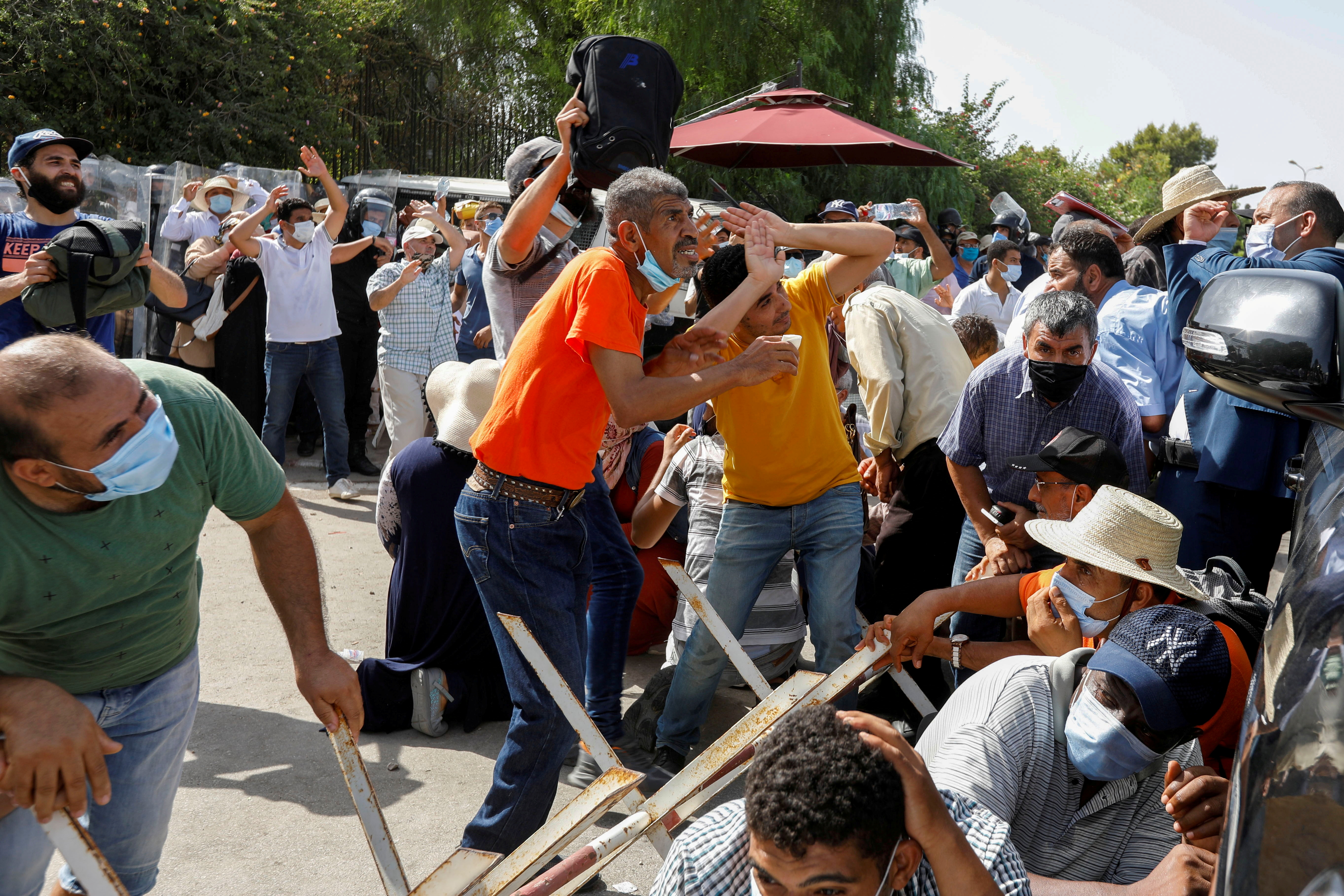 Supporters of Tunisia&#39;s biggest political party, Ennahda, take cover from stones thrown at them by supporters of President Kais Saied, outside the parliament building in Tunis, Tunisia July 26, 2021. [Zoubeir Souissi/Reuters]