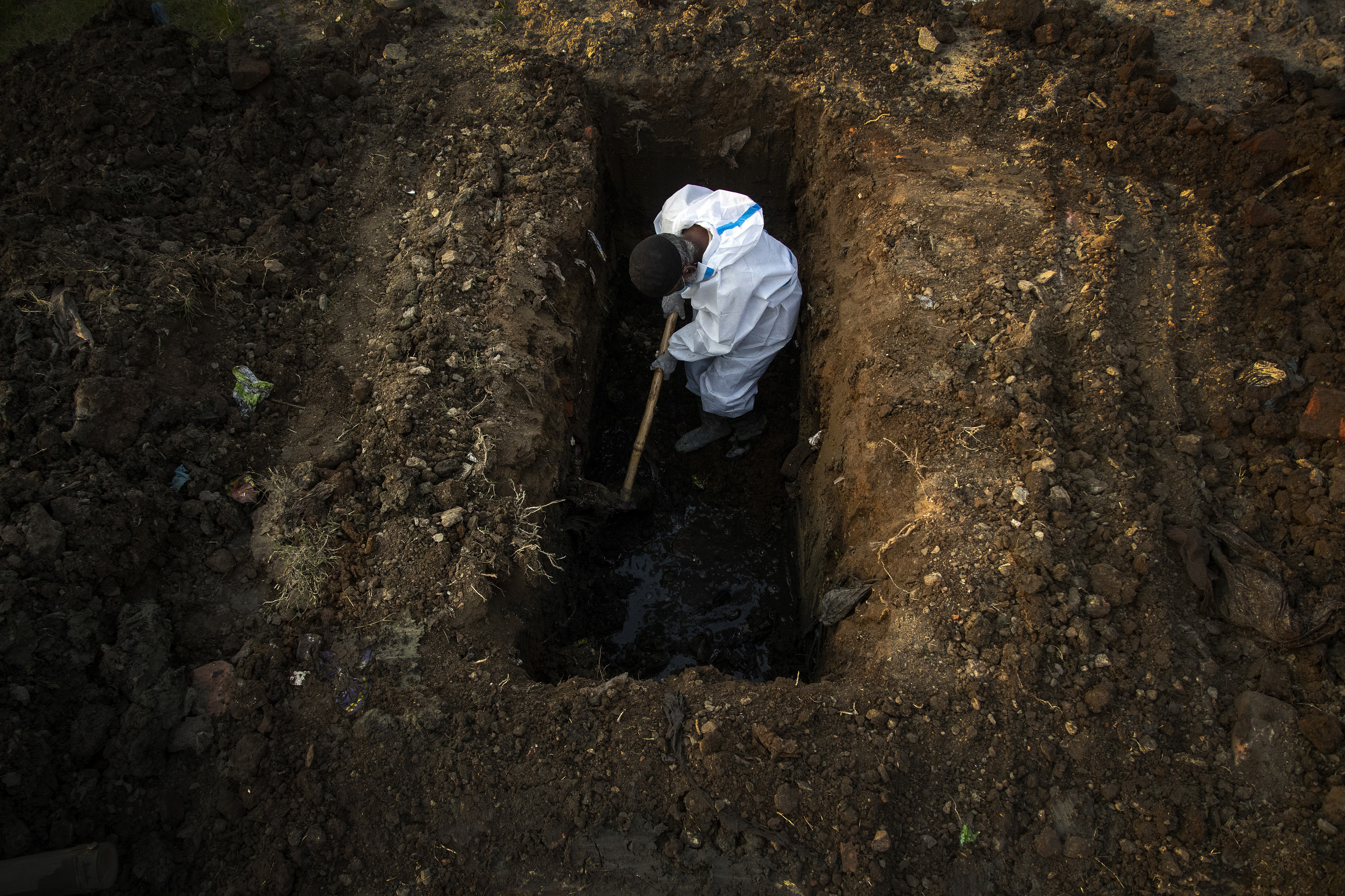 In this April 25, 2021 photo, a man in protective suit buries the body of a person who died of COVID-19 in Guwahati, India [File: Anupam Nath/AP]