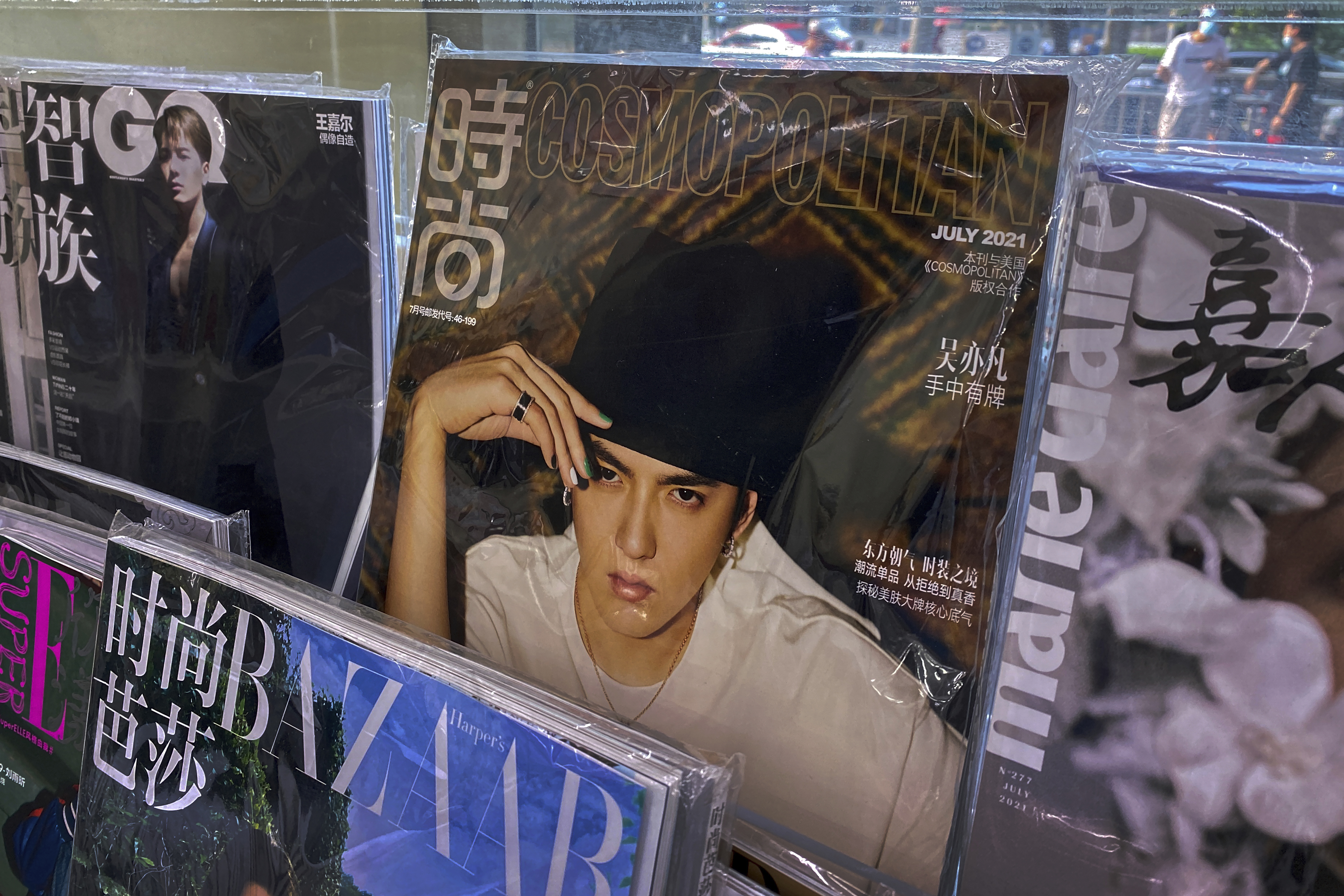 A fashion magazine showing Chinese-Canadian singer Kris Wu, centre, on display in Beijing [File: Andy Wong/ AP]