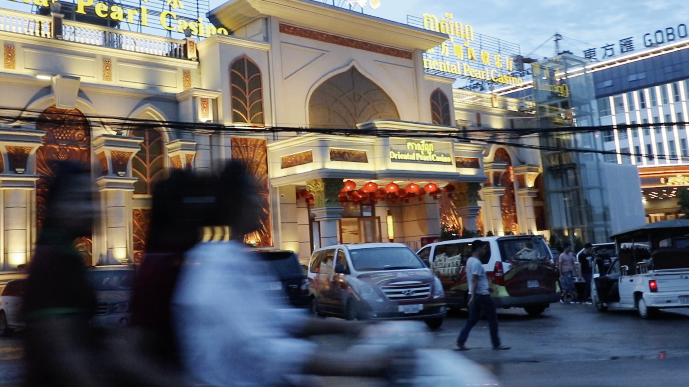 Women drive past a casino in Sihanoukville, a coastal city that has become a gambling boom town [Lindsey Kennedy/Al Jazeera]