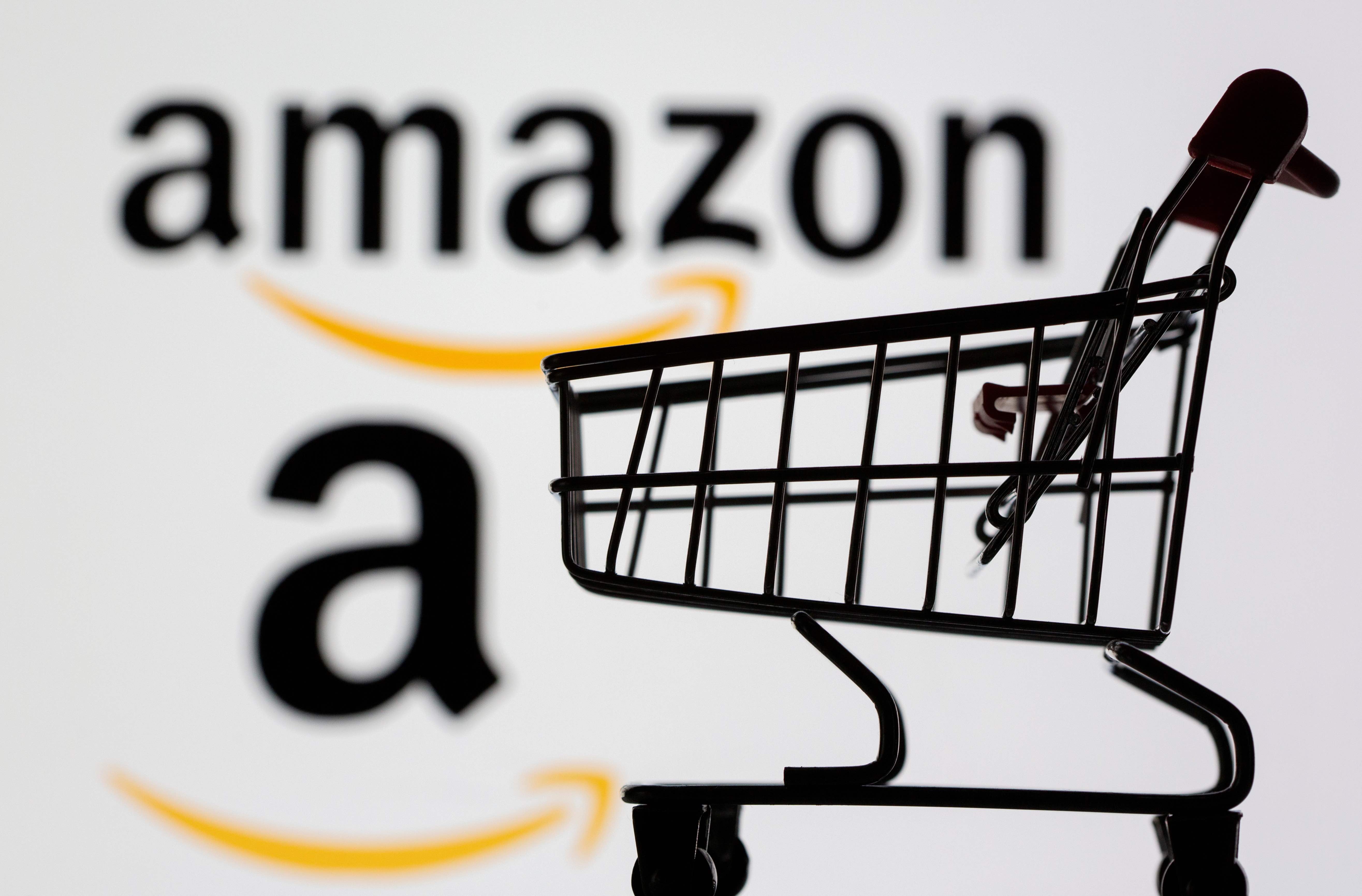 Small toy shopping cart is seen in front of displayed Amazon logo in this illustration, taken July 30, 2021.
