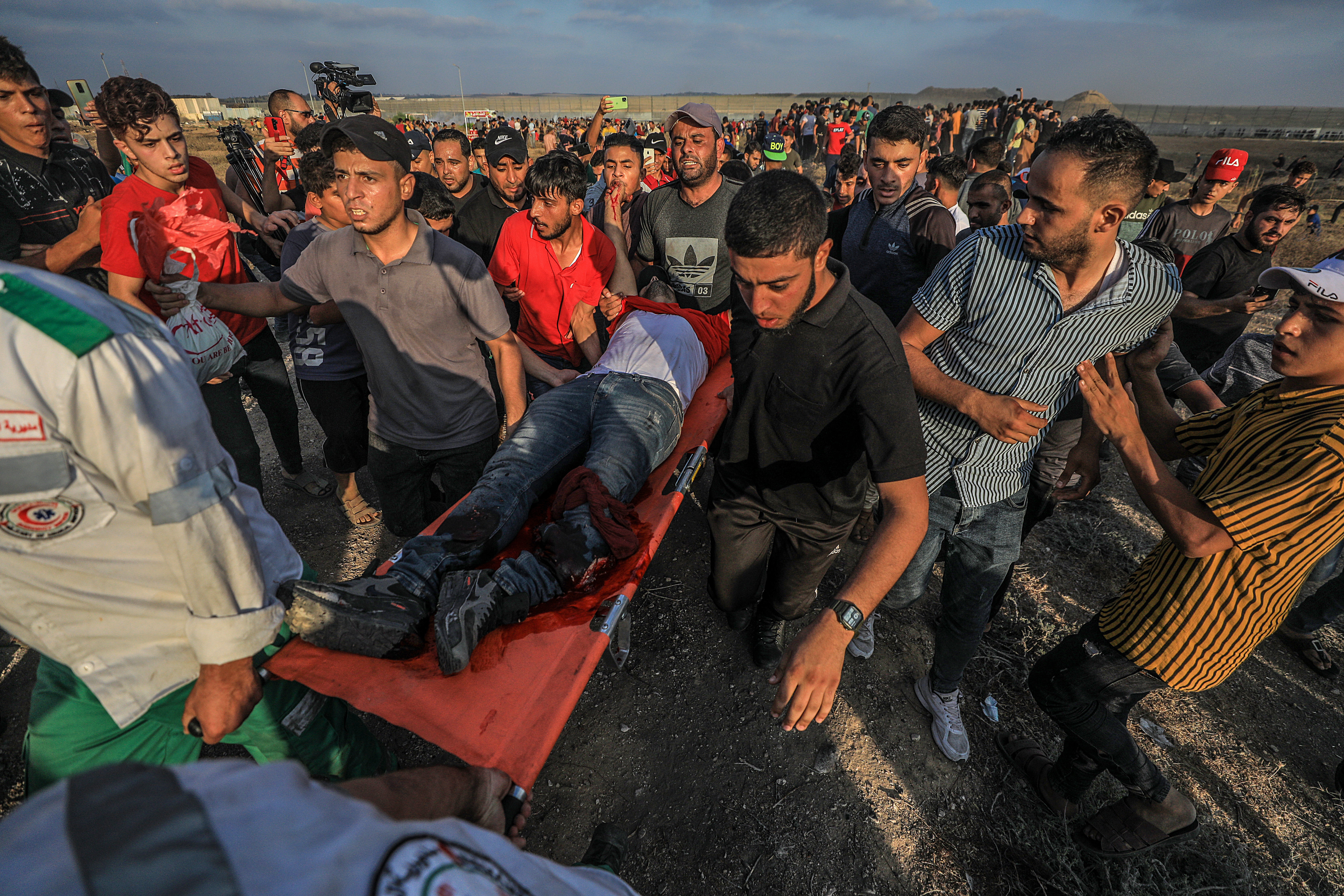 Palestinian protesters carry a wounded man during the clahses near the separation barrier between Israel and Gaza Strip [Mohammed Saber/EPA]