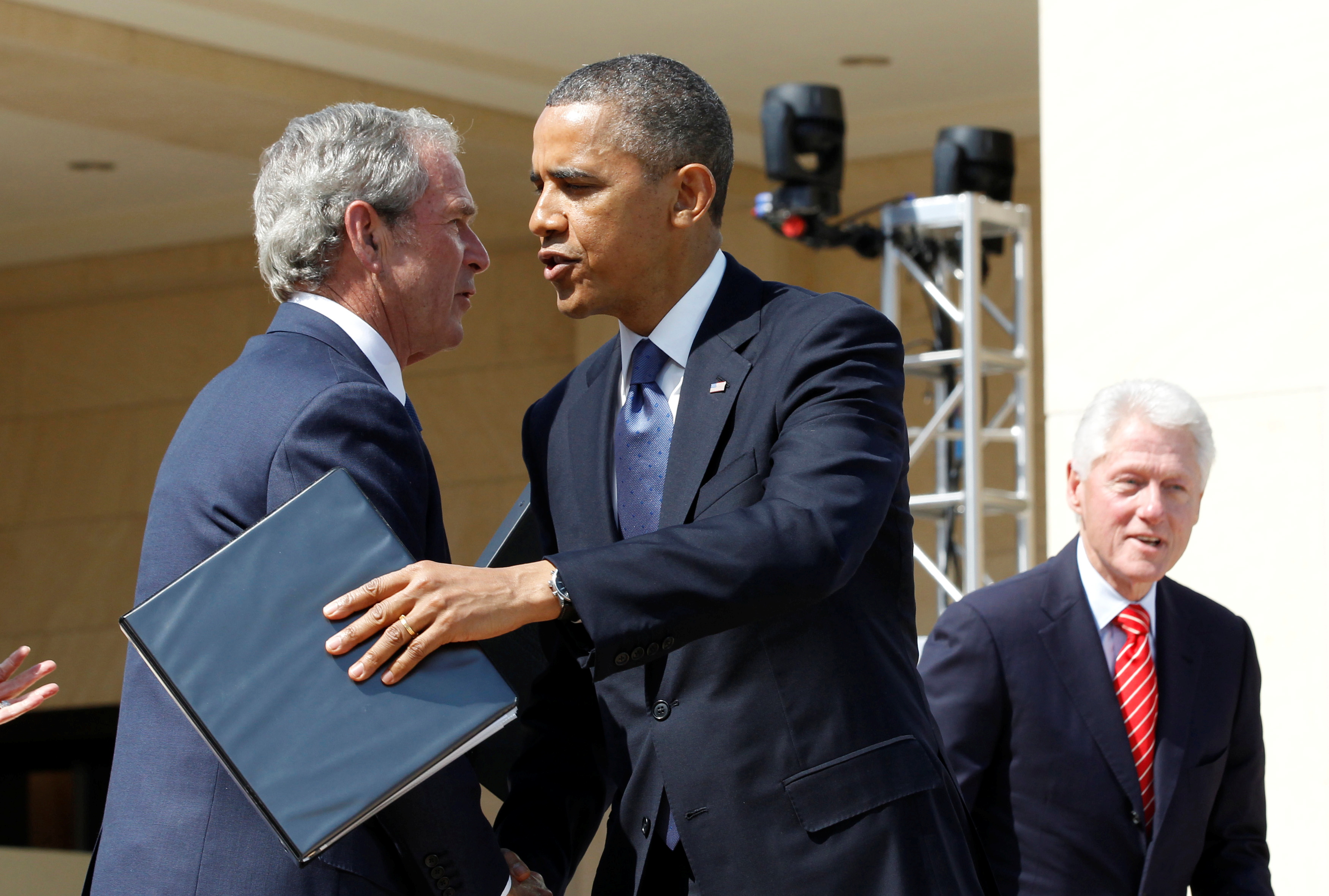 US President Barack Obama embraces former President George W Bush with former president Bill Clinton pictured at right [File: Jason Reed/Reuters]