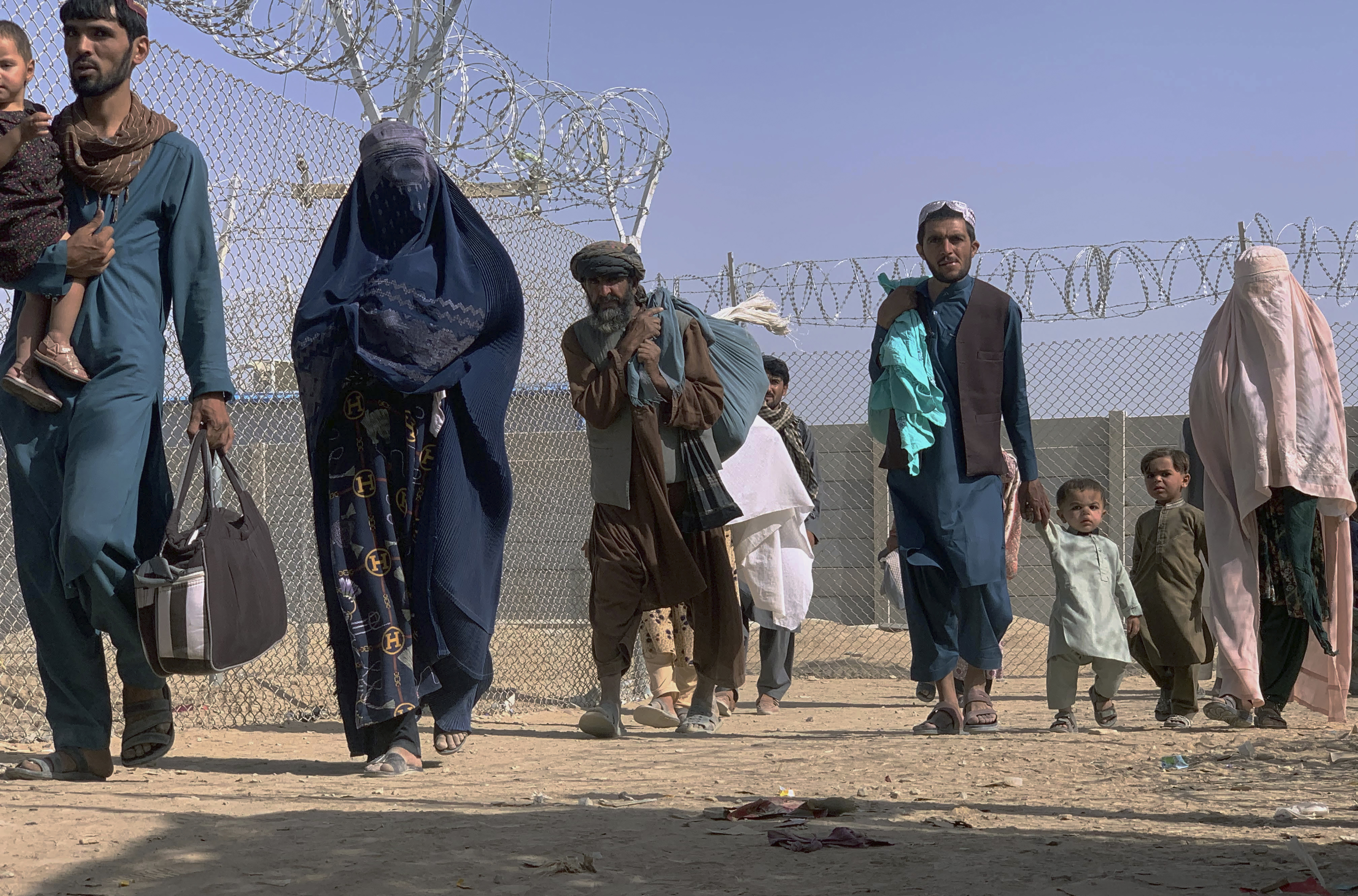 Afghans walk through a security barrier as they enter Pakistan through a common border crossing point in Chaman, Pakistan [File: AP Photo]