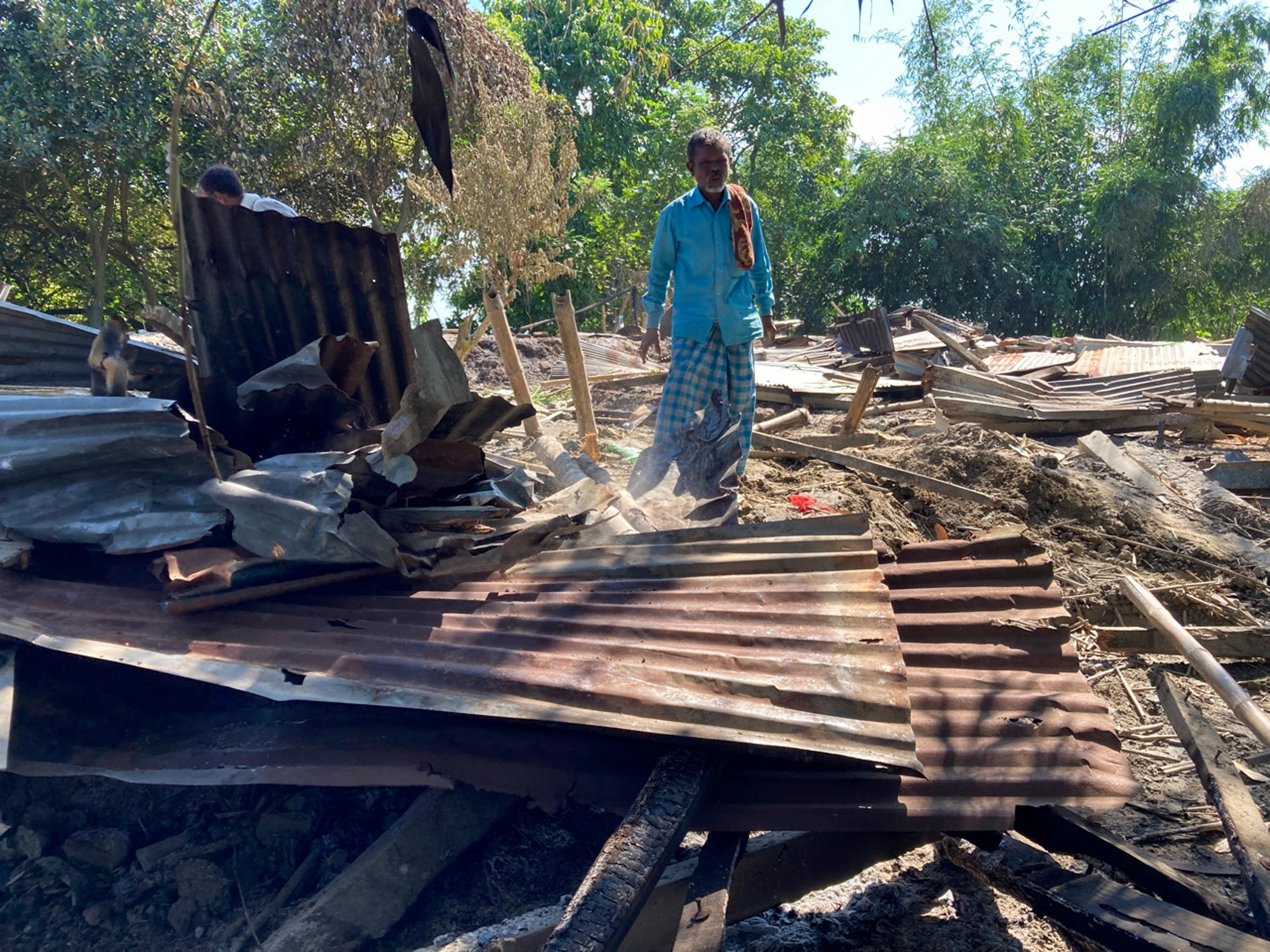 Kamaruddin, surrounded by tin sheets which formed his old house. Now he lives next to the river [Sadiq Naqvi/Al Jazeera]
