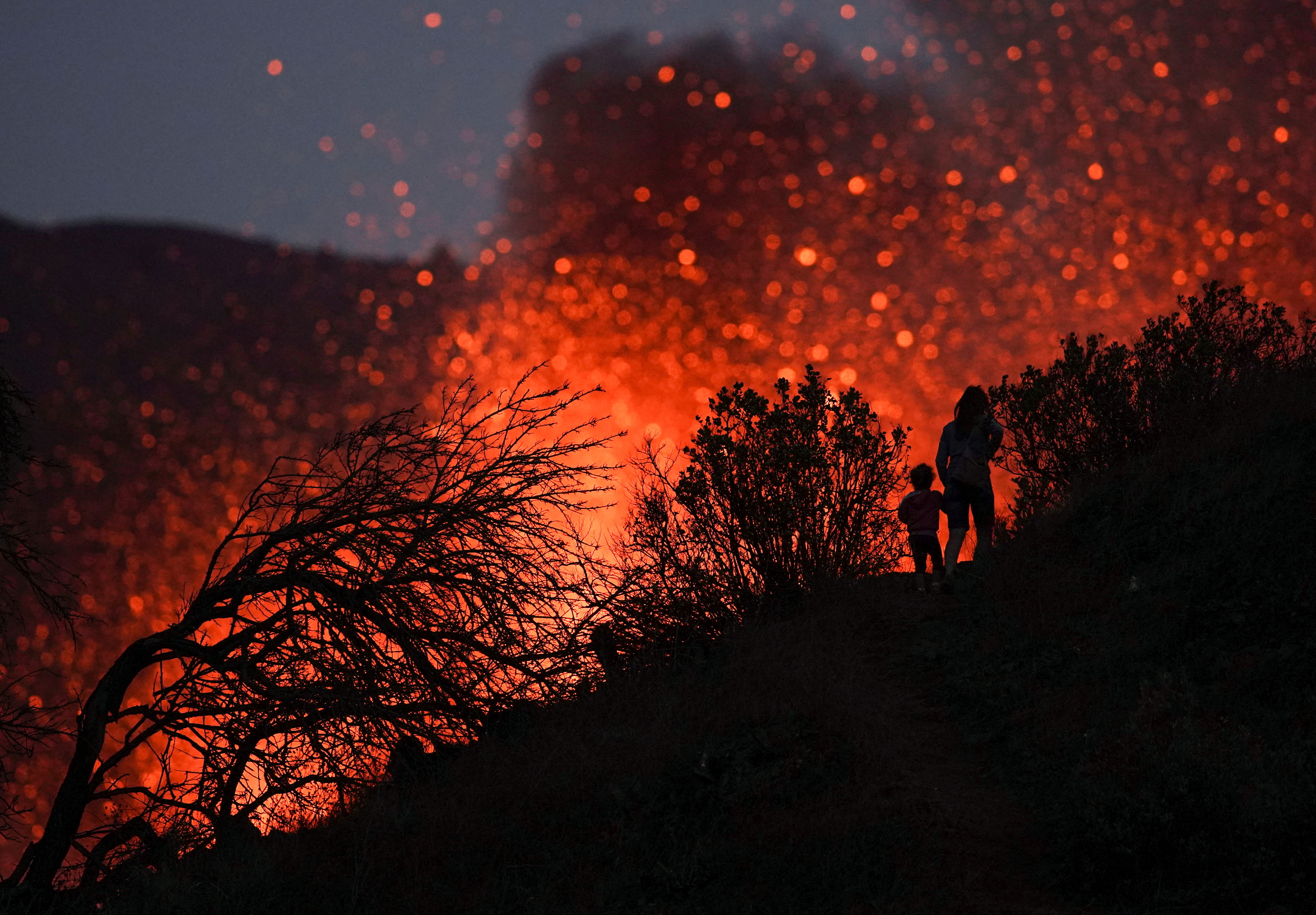 A woman climbs a hill with a child to see the Cumbre Vieja volcano as it continues to erupt in Tacande de Arriba on the Canary Island of La Palma, Spain, October 2, 2021. [Juan Medina/ TPX]