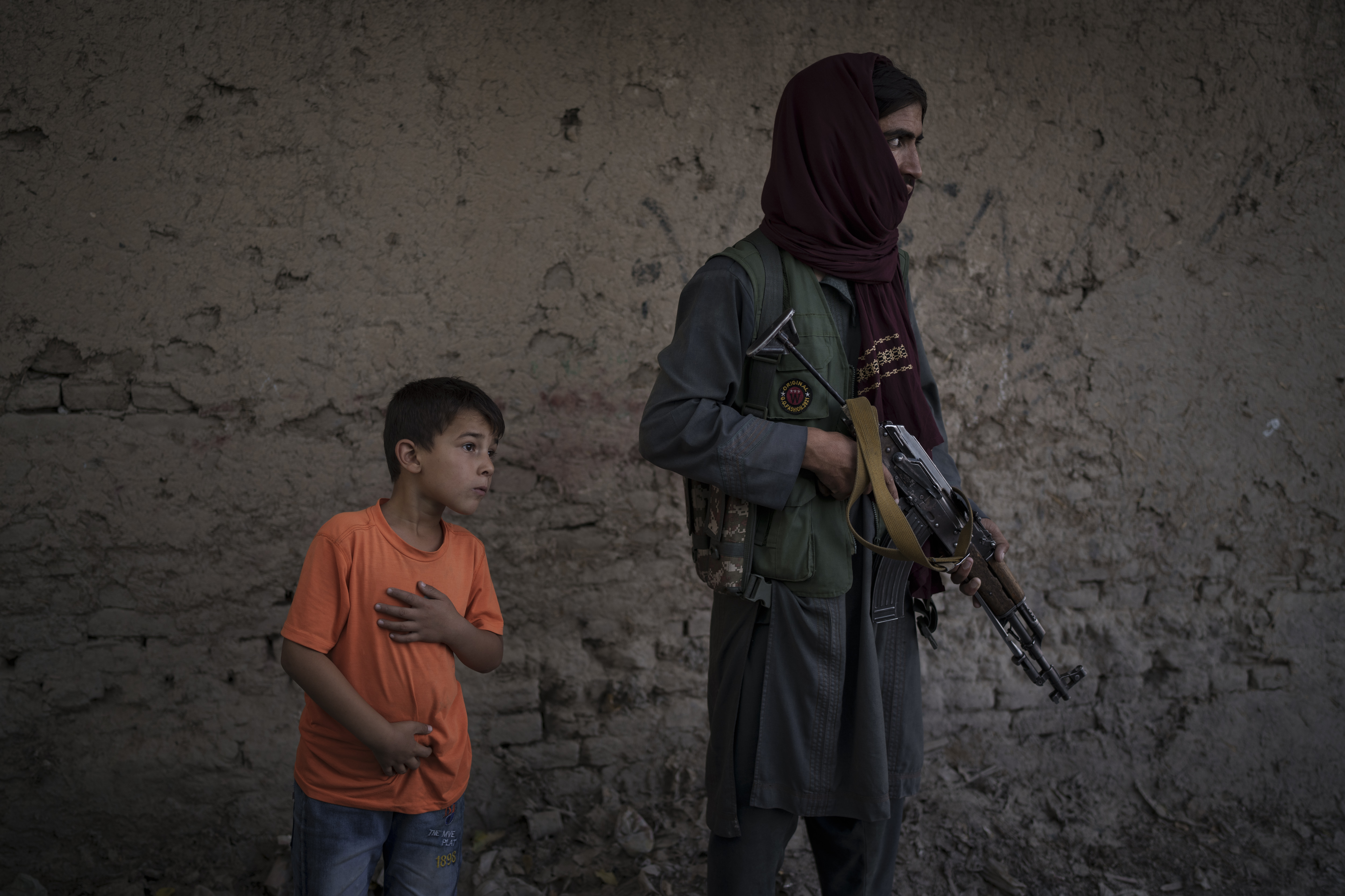 An Afghan boy watches as Taliban fighters search for a man accused of a stabbing in Kabul. [Felipe Dana/AP Photo]