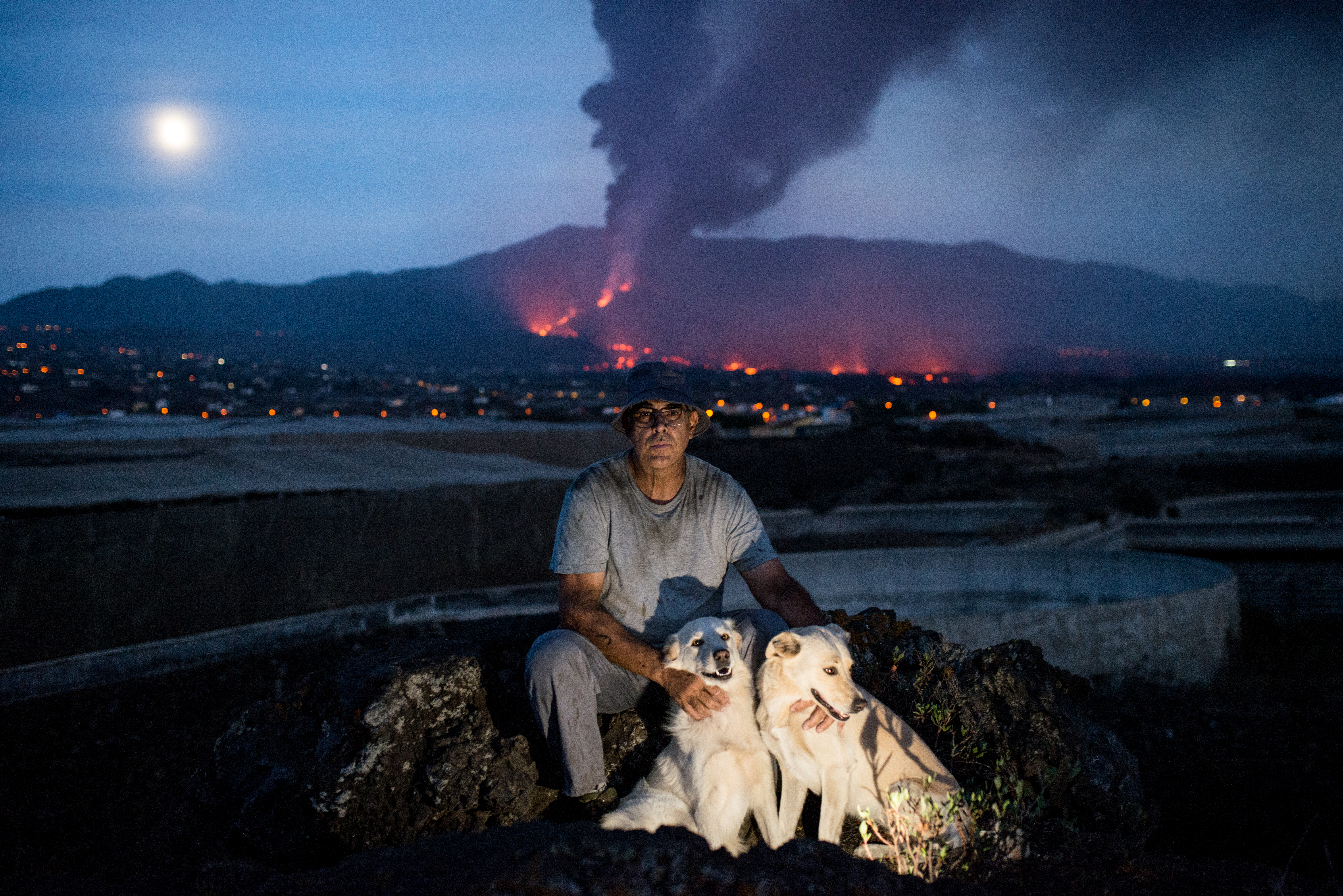 Banana farmer Jose Alvaro Leon Diaz rests with his dogs at the end of a day spent trying to salvage his crop from the ashfall. &#39;When we try to sell them it looks like the bananas have been sanded down. Inside it’s the same, it’s tasty. But on the outside, to the eye, it doesn&#39;t sell.&#39; [Alexander Lerche/Al Jazeera]