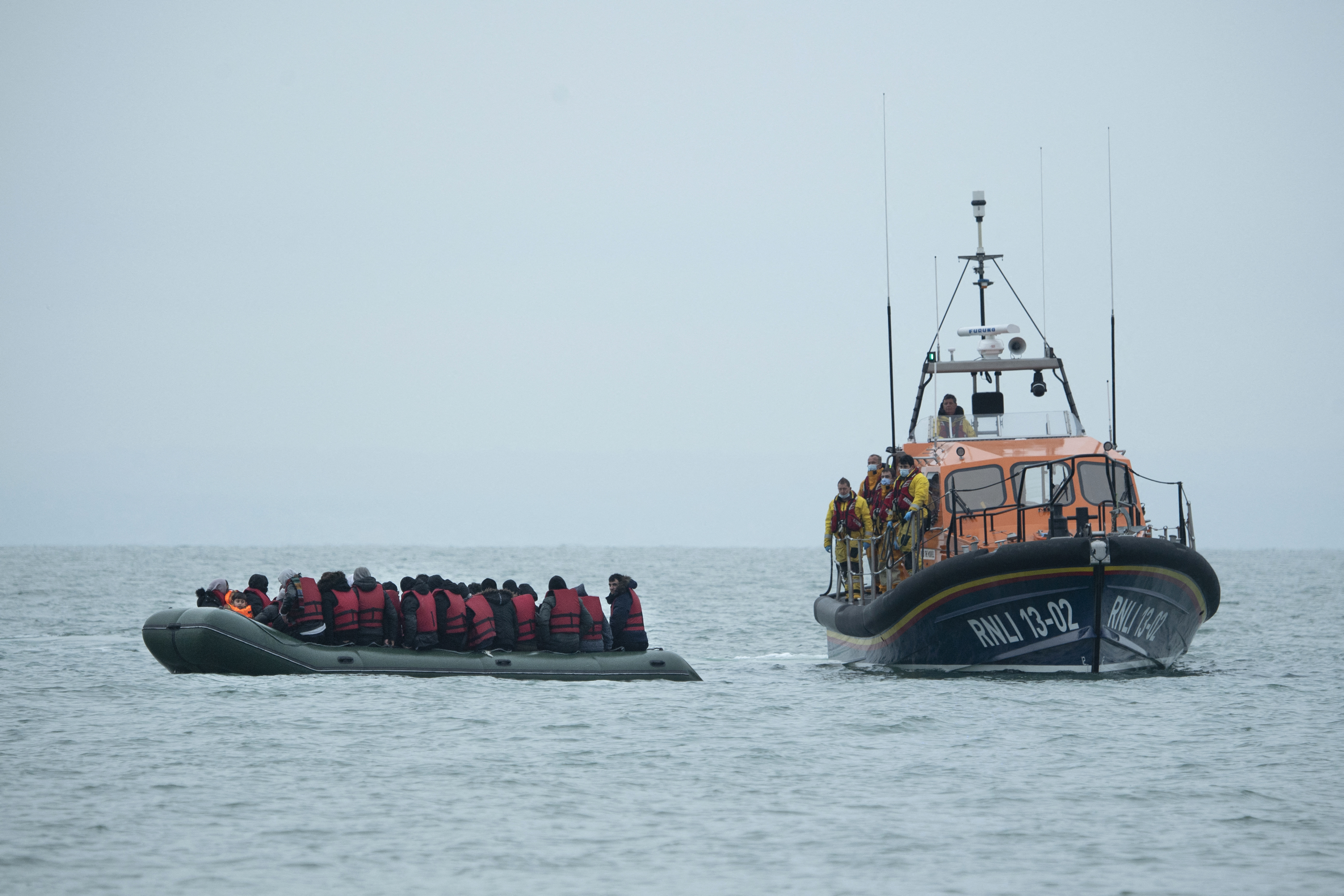 Migrants are helped by a RNLI (Royal National Lifeboat Institution) lifeboat before being taken to a beach in Dungeness, on the southeast coast of England, on November 24, 2021, after crossing the English Channel [Ben Stansall/AFP]
