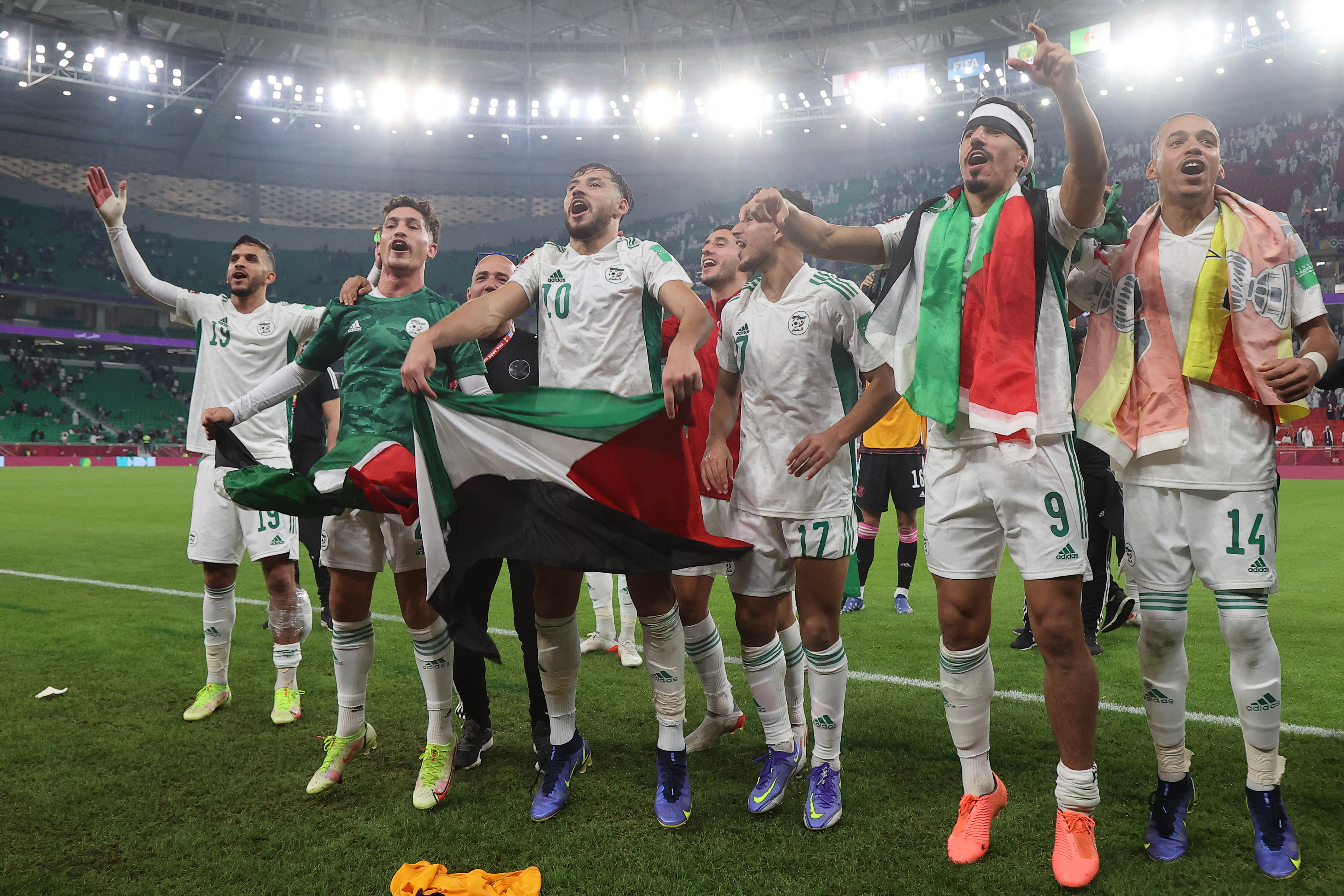 Algeria&#39;s players wave Palestinian national flags after winning the FIFA Arab Cup 2021 semi-final football match between Qatar and Algeria at the Al-Thumama Stadium in the Qatari capital of Doha on December 15, 2021 [File: Karim Jaafar/AFP]