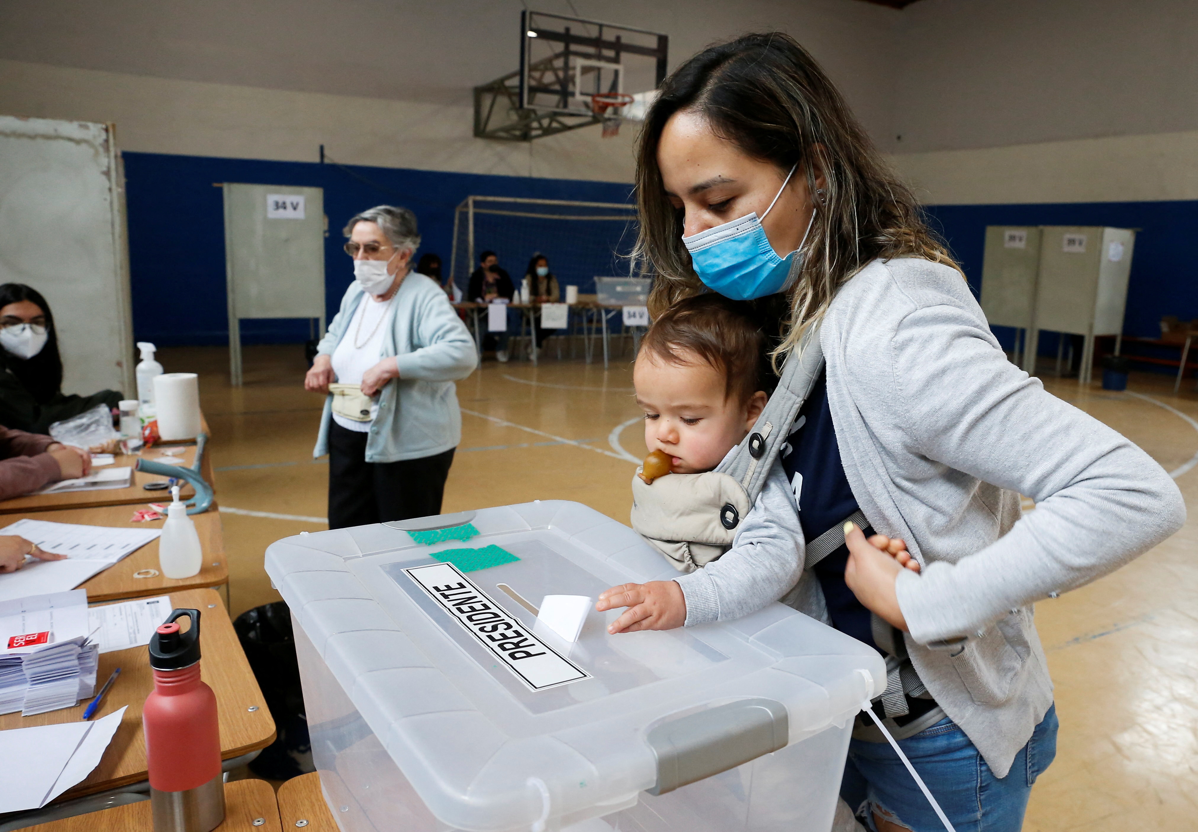 A child casts a ballot on behalf of the mother during the presidential election at a polling station in Santiago, Chile [Rodrigo Garrido/Reuters]