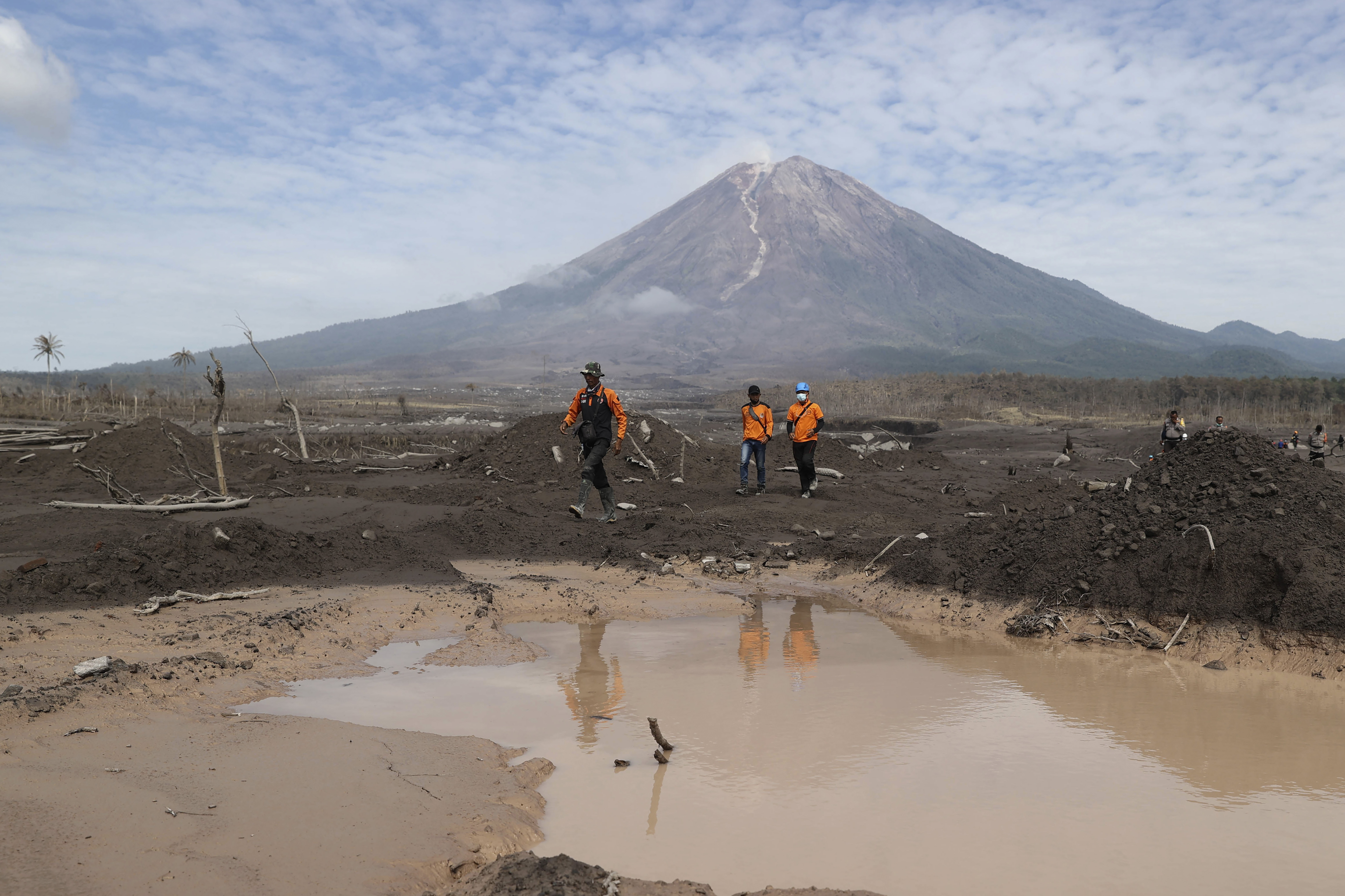 Rescuers walk on an area affected by the eruption of Mount Semeru during a search for victims in Lumajang, East Java, Indonesia, Wednesday, December 8, 2021 [Trisnadi/ AP]