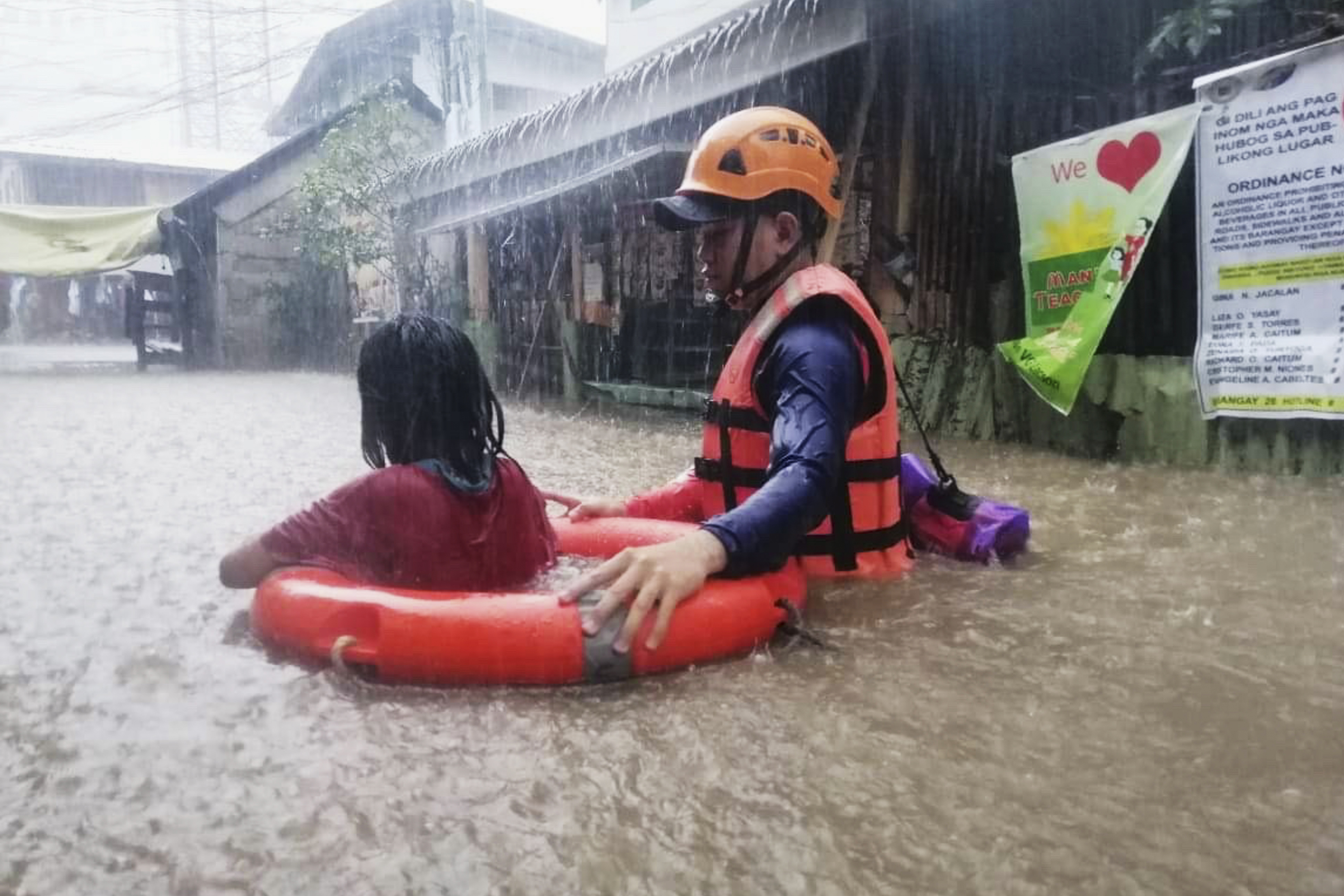 Rescuer assists a girl as they wade through flooding caused by Typhoon Rai in Cagayan de Oro City, southern Philippines on Thursday, December 16, 2021 [Philippine Coast Guard via AP]